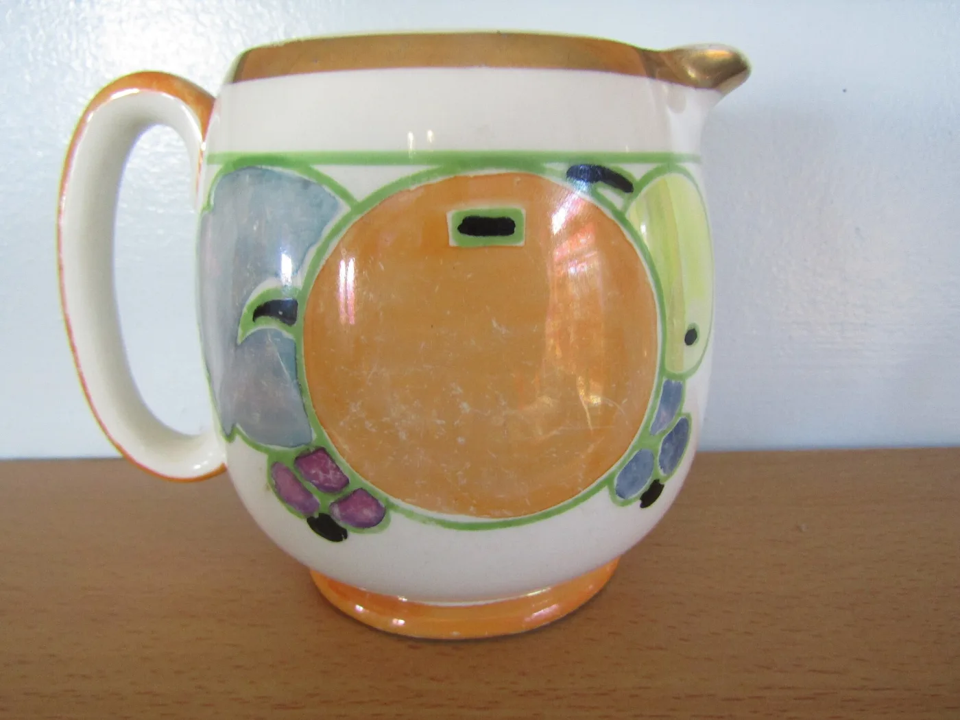 Cream jug banded in orange lustre with a hand-painted abstract flower panel in green, blue, mauve and black