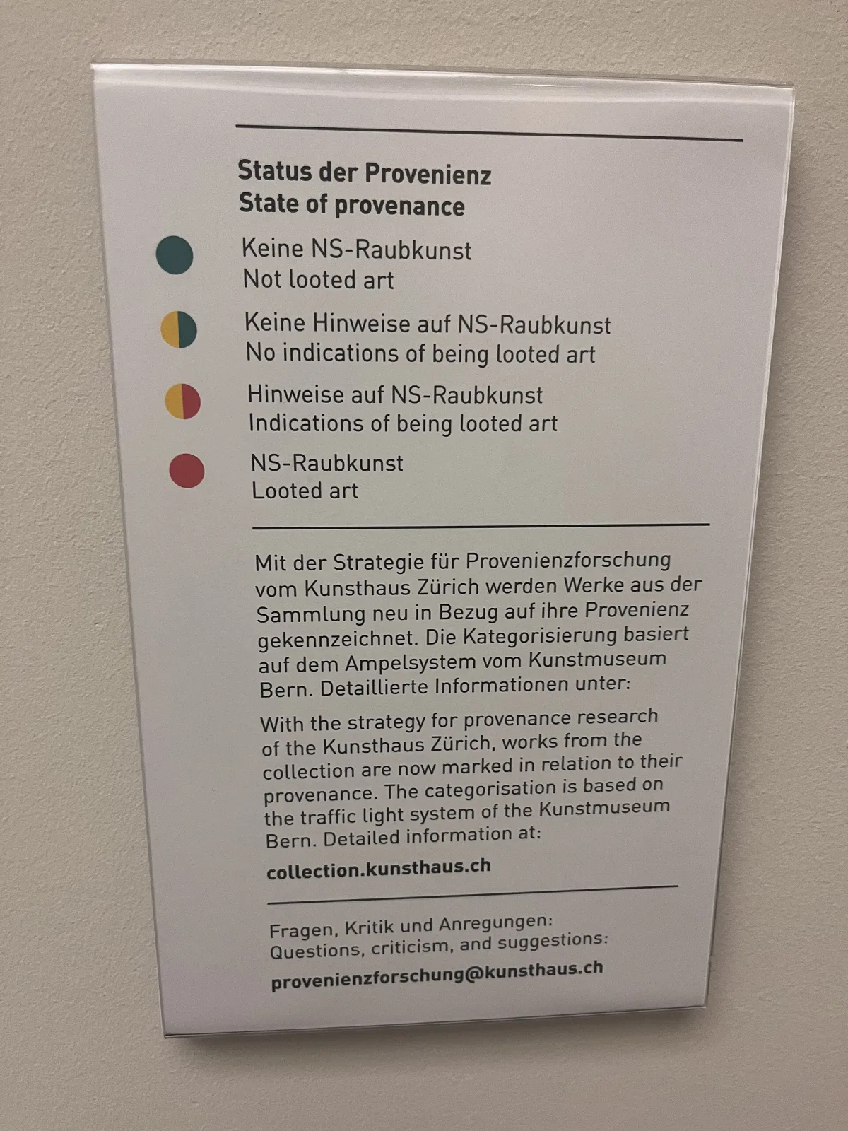 Museum wall panel headed State of provenance, listing four coloured dots against four categories from not looted art to looted art, in German and English