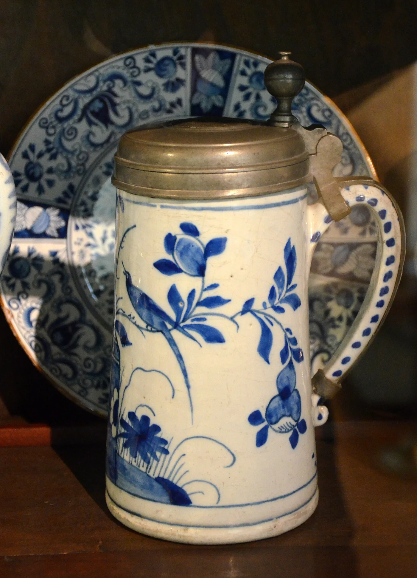 Dutch tankard of 1750 in blue and white with a pewter lid, shown beside a matching plate