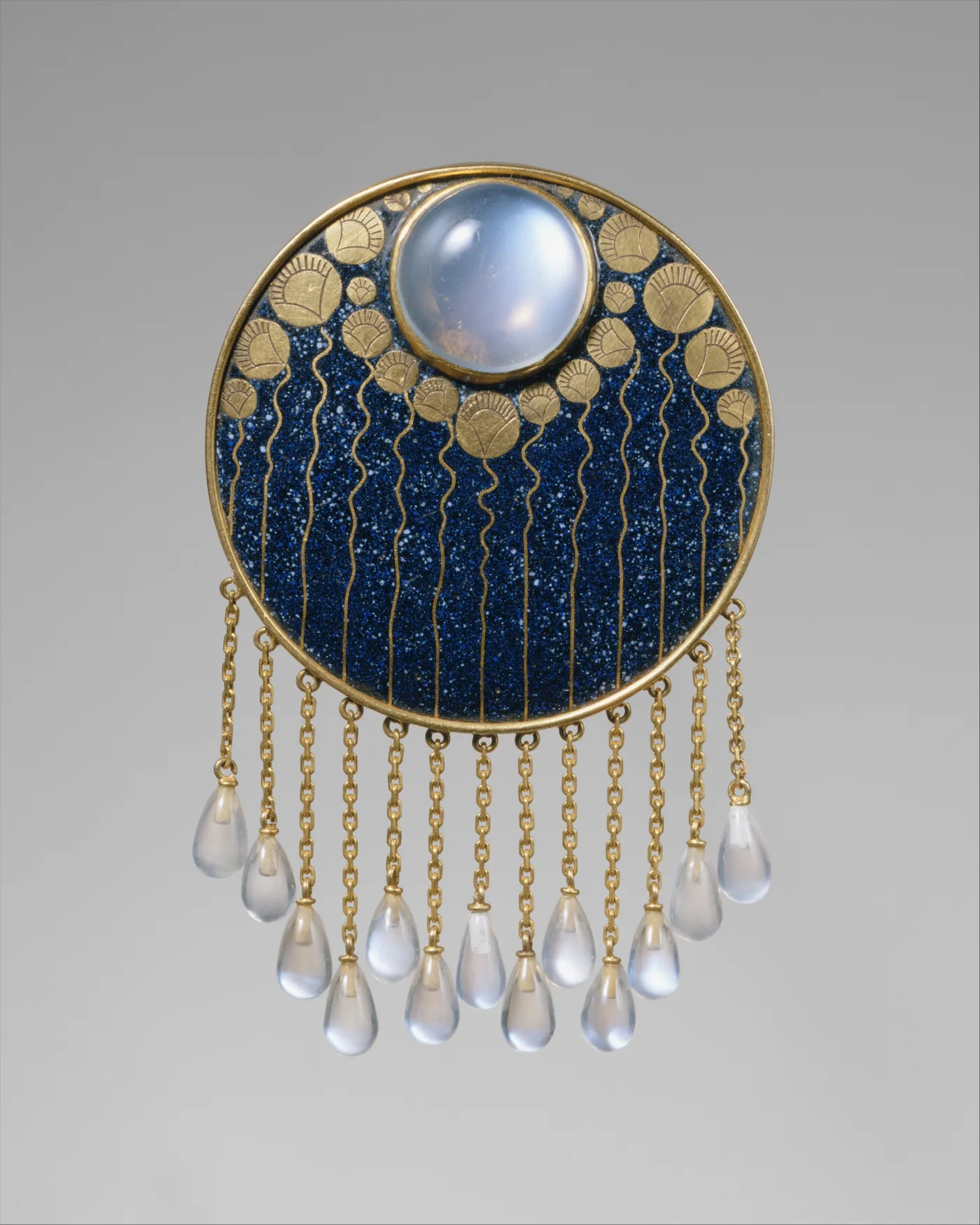 Circular gold brooch inlaid with dark blue lapis lazuli, a large moonstone cabochon at the top and a fringe of moonstone drops on gold chains