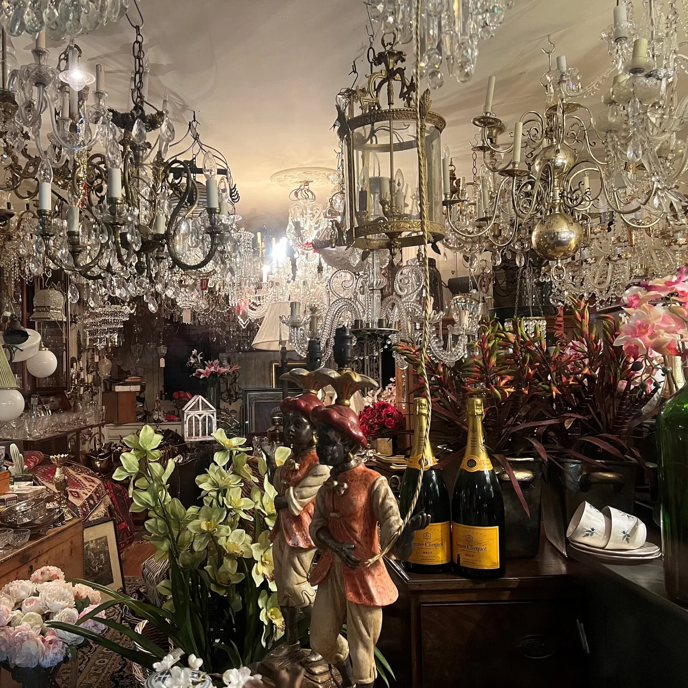 Interior of a small English antique shop packed with furniture, glassware, framed pictures and brass, filling every shelf and much of the floor