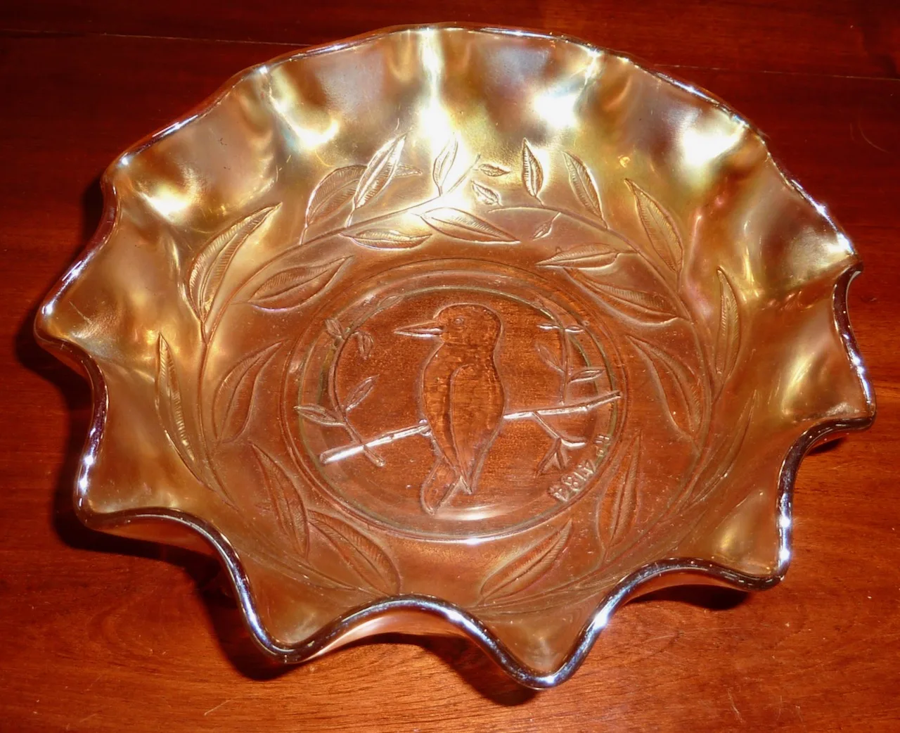Ruffled carnival glass bowl photographed at an angle with flash, reading warm orange and gold across the whole surface