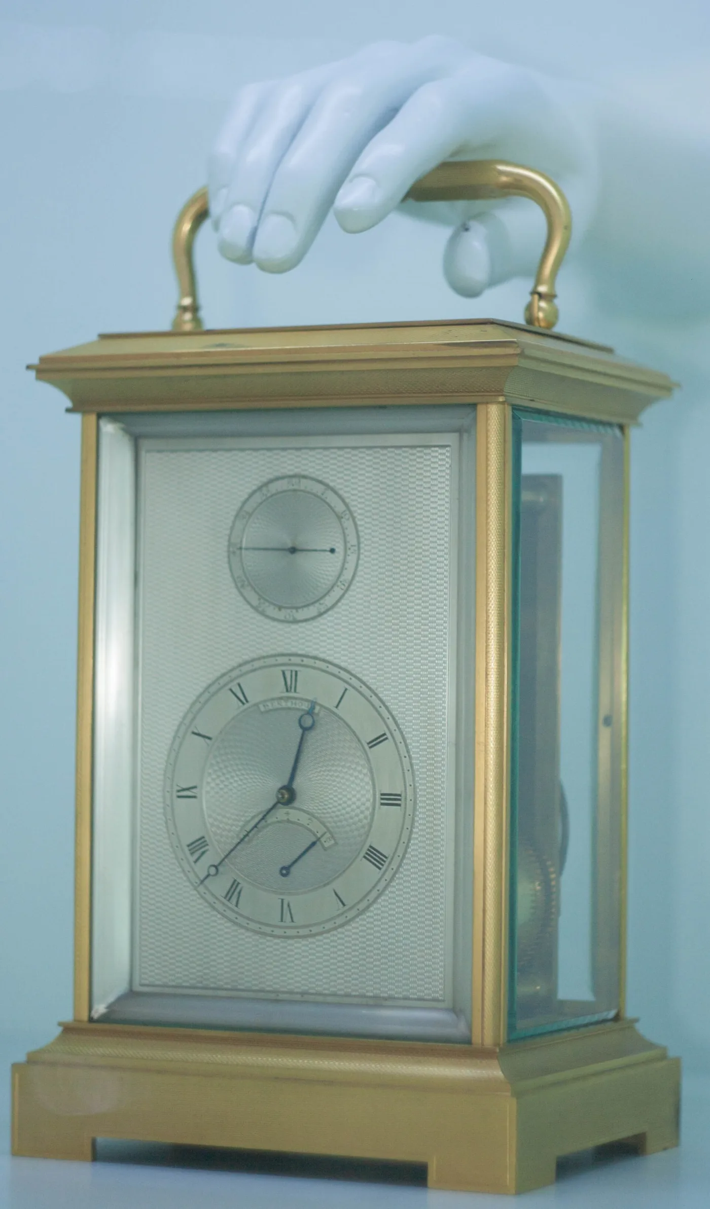 Gilt brass carriage clock with bevelled glass panels, a folding top handle and a silvered engine-turned dial with a subsidiary alarm dial