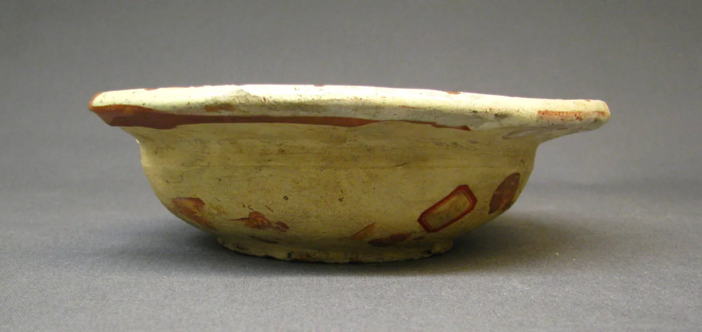 The same dish photographed from the side at eye level, showing a shallow bowl with a wide flat flange and a slightly uneven profile
