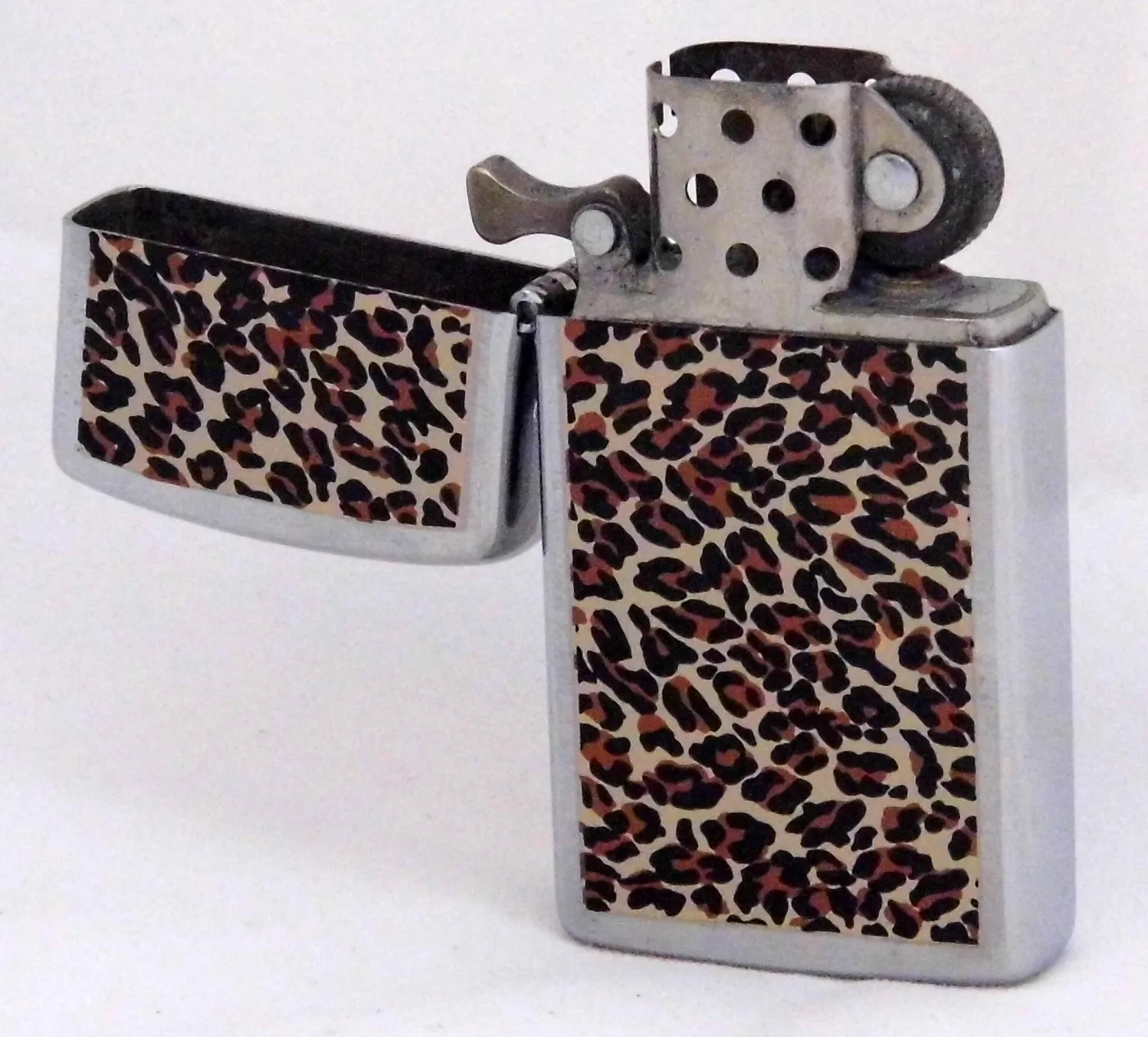 Chrome flip-top lighter standing open, the lid hinged back, showing the loose inner unit with its perforated chimney, cam and flint wheel, and a leopard-print panel applied to both case halves
