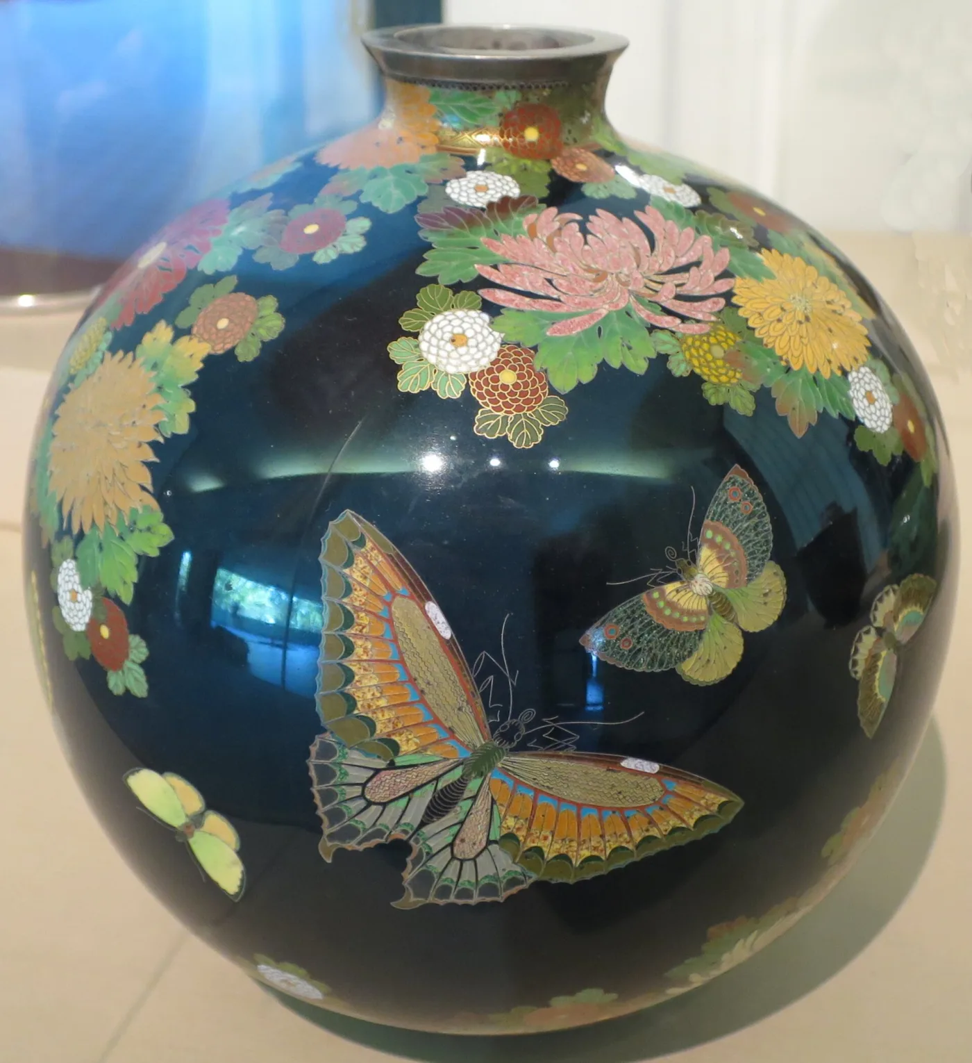 A cloisonne vase with butterflies and chrysanthemums on a dark ground, the design dense and very finely drawn
