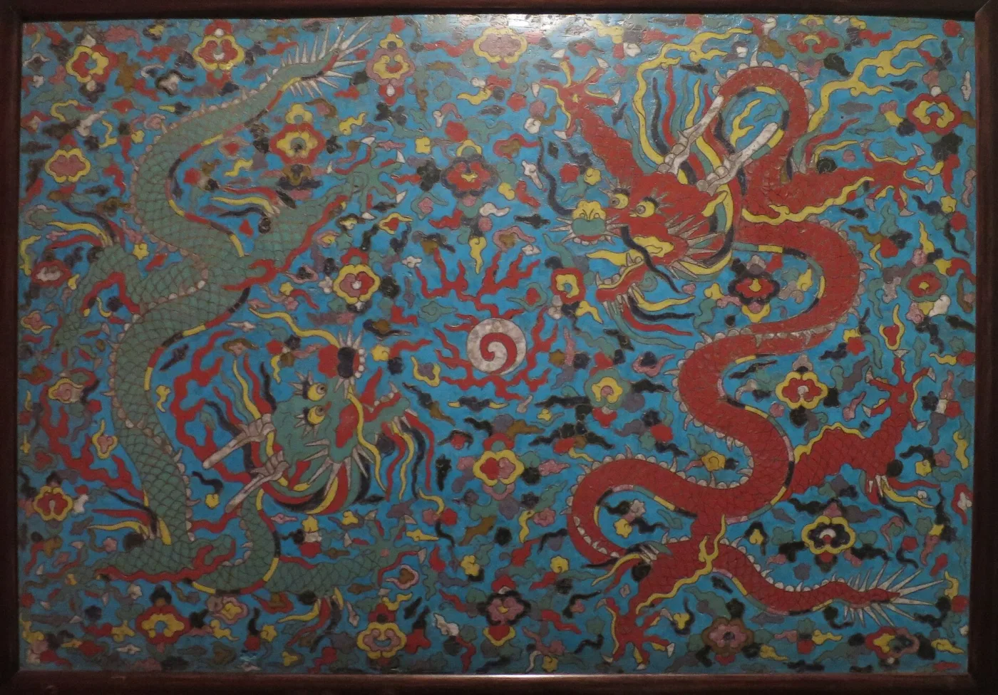 A cloisonne panel worked with confronting dragons among scrolling clouds on a turquoise ground