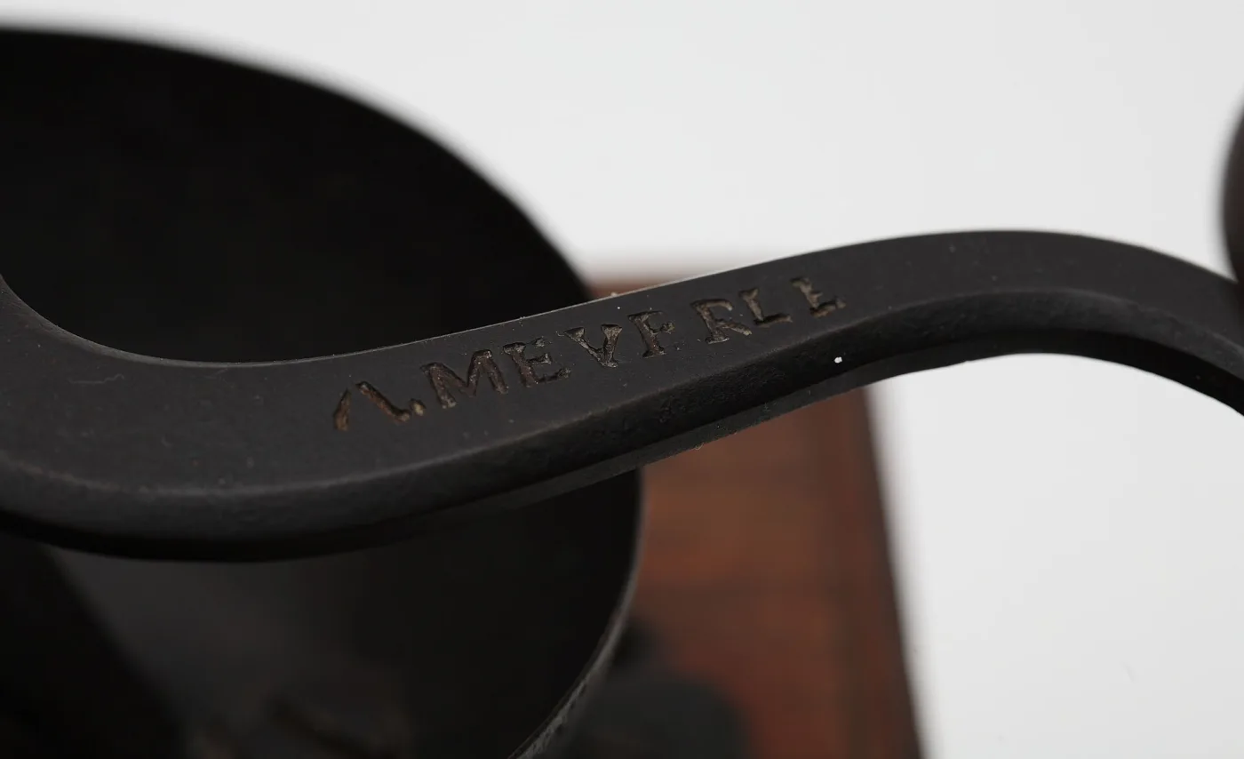Close-up along a black cast-iron crank arm, its upper face carrying the raised cast letters A. MEVERLL