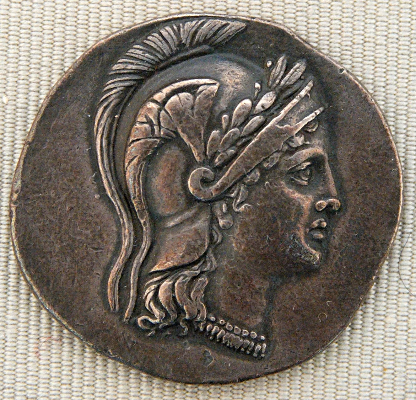 Toned silver coin showing the head of Athena in profile to the right, wearing a crested helmet and a laurel wreath, struck in high relief within a beaded border