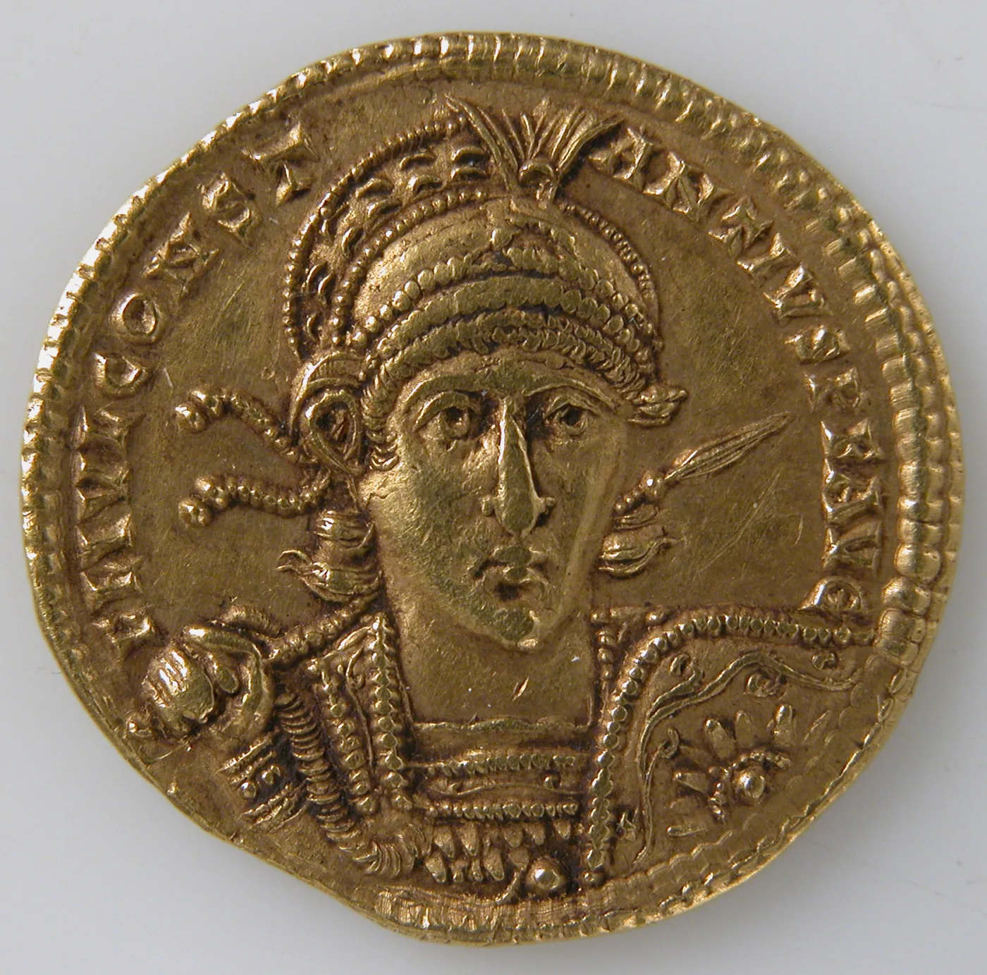 Thick gold coin with a helmeted bust facing forward holding a spear and shield, surrounded by a legend reading CONSTA on the left and NTIVS P F AVG on the right, within a beaded border
