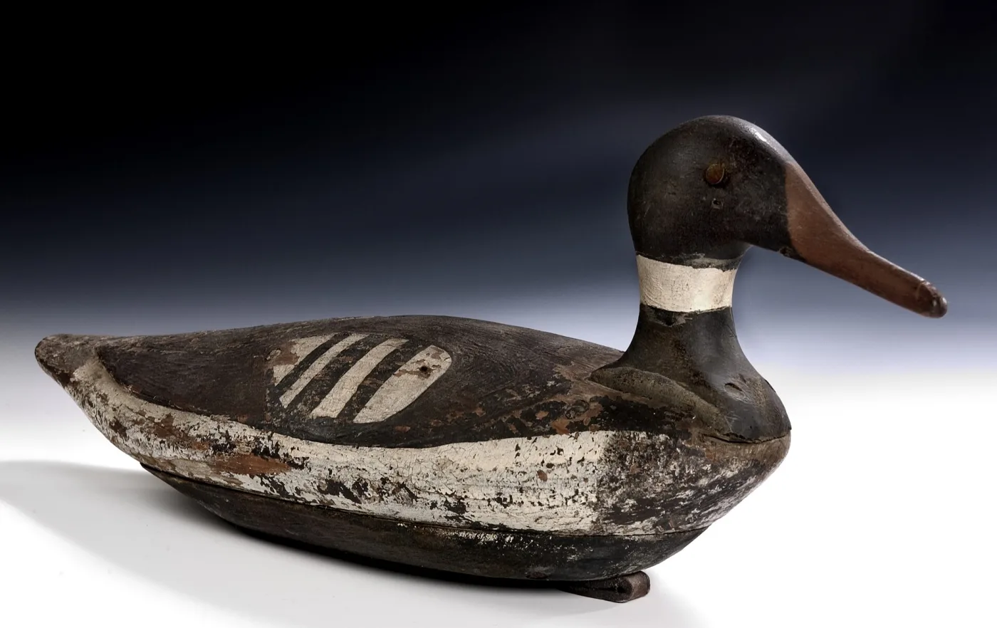 Merganser drake decoy with a black head, white neck ring and white flank stripes, the paint worn to bare wood on the crown, breast and bill