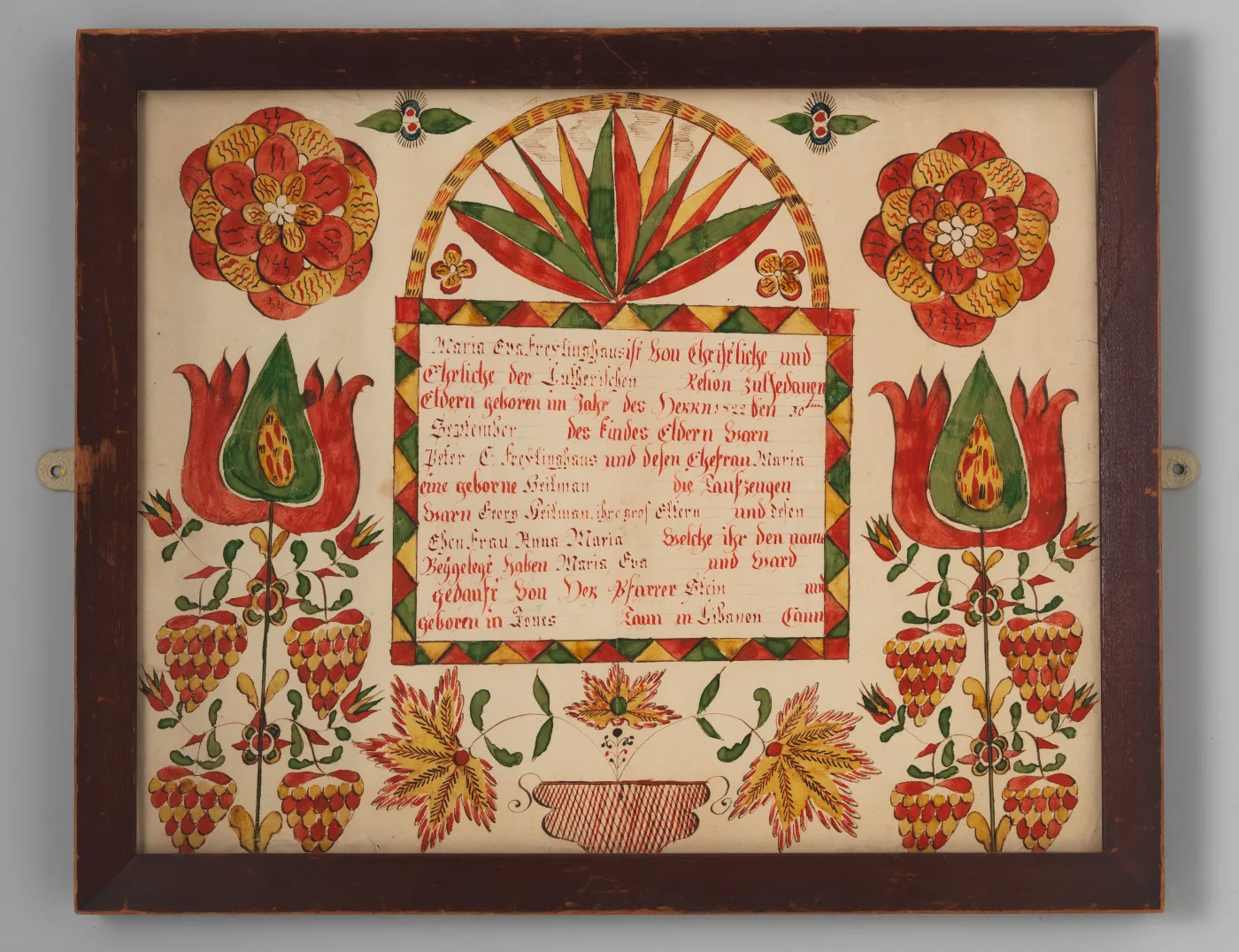 Framed Pennsylvania German birth and baptismal certificate with red and yellow rosettes, tulips, strawberries and a fan-shaped arch over a block of red script