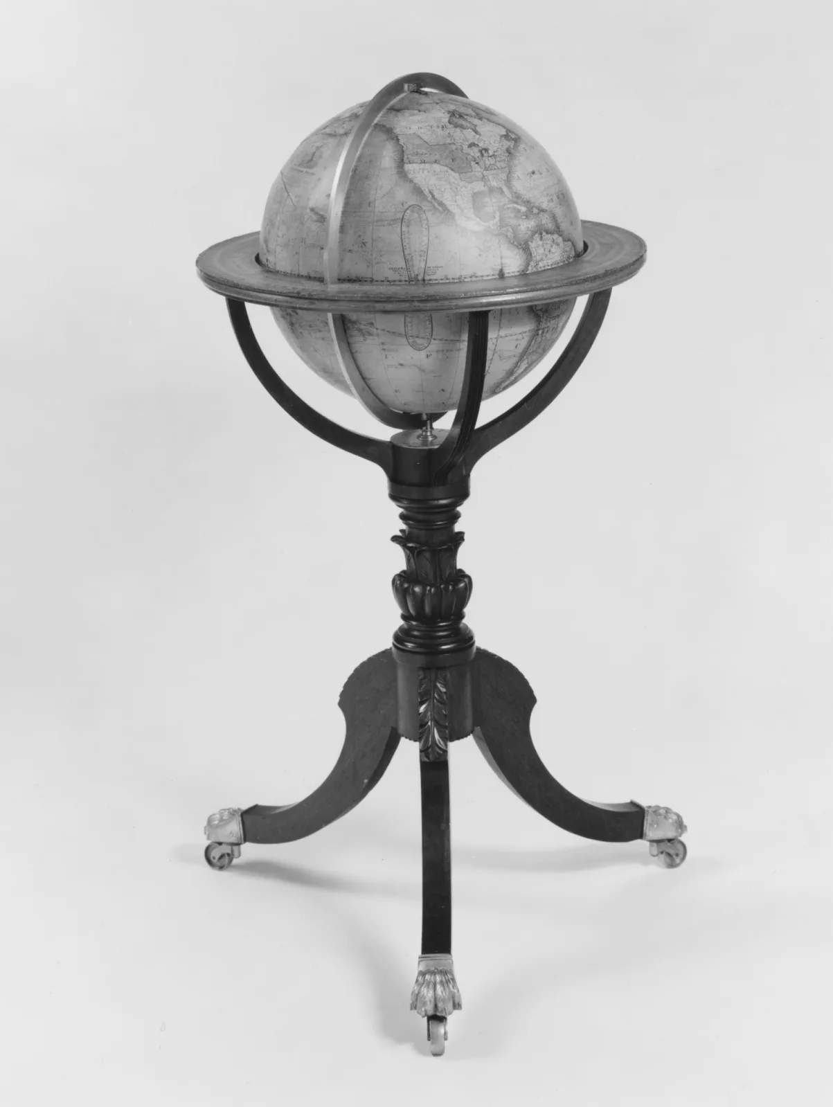 Globe printed with a world map, mounted in a brass meridian ring on a slender turned column with three splayed legs