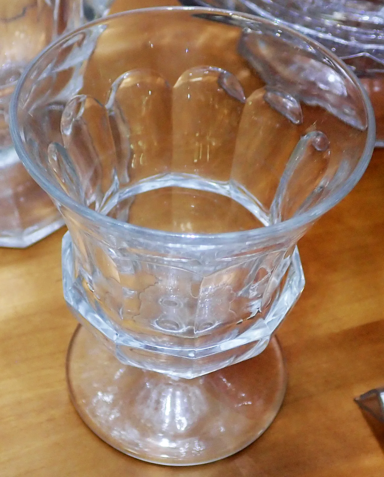 Clear pressed glass egg cup with wide vertical panels and a scalloped rim