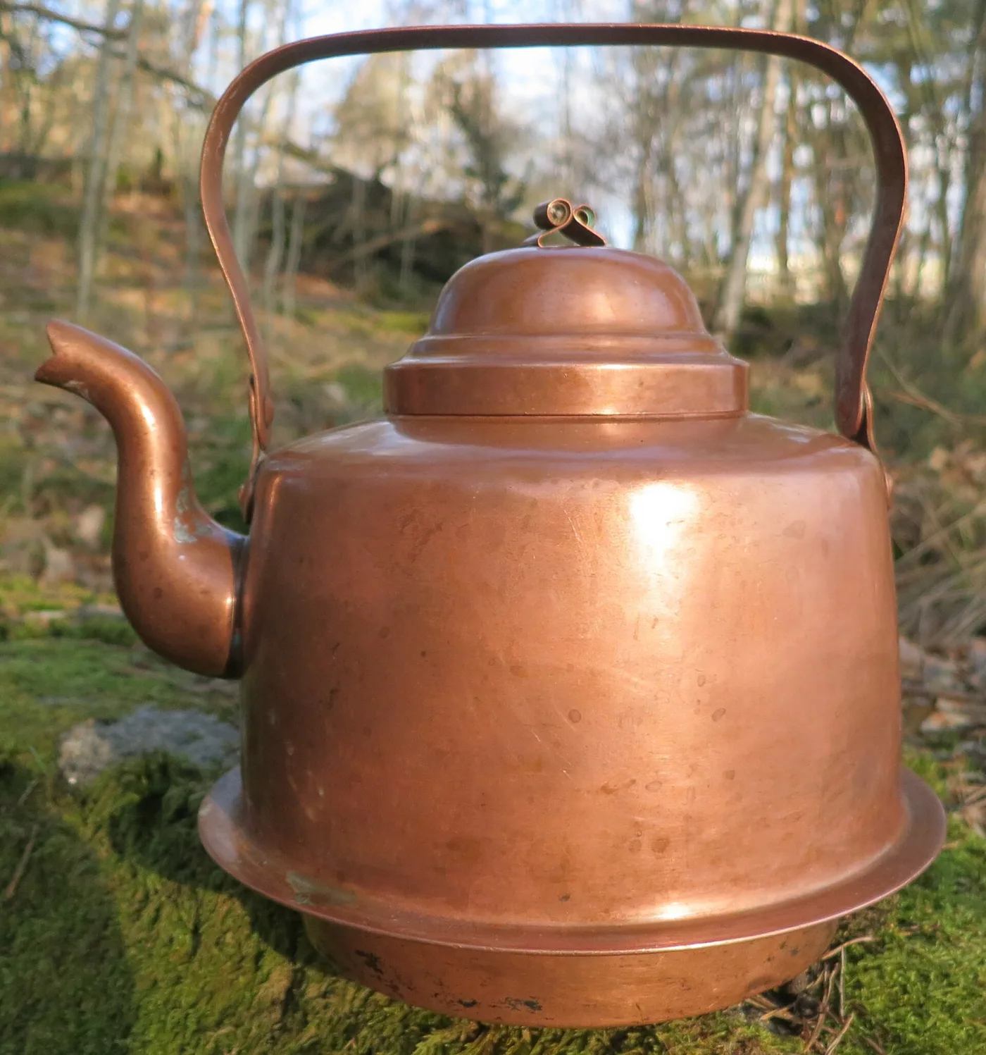 Polished copper kettle with a flared skirt at the base, domed lid, swan-neck spout and a flat copper swing handle