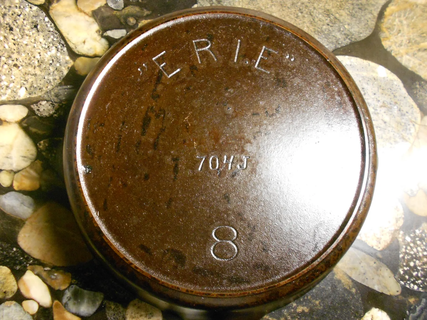 Underside of a cast iron pan showing only the raised word ERIE in quotation marks above a pattern number and a size number 8