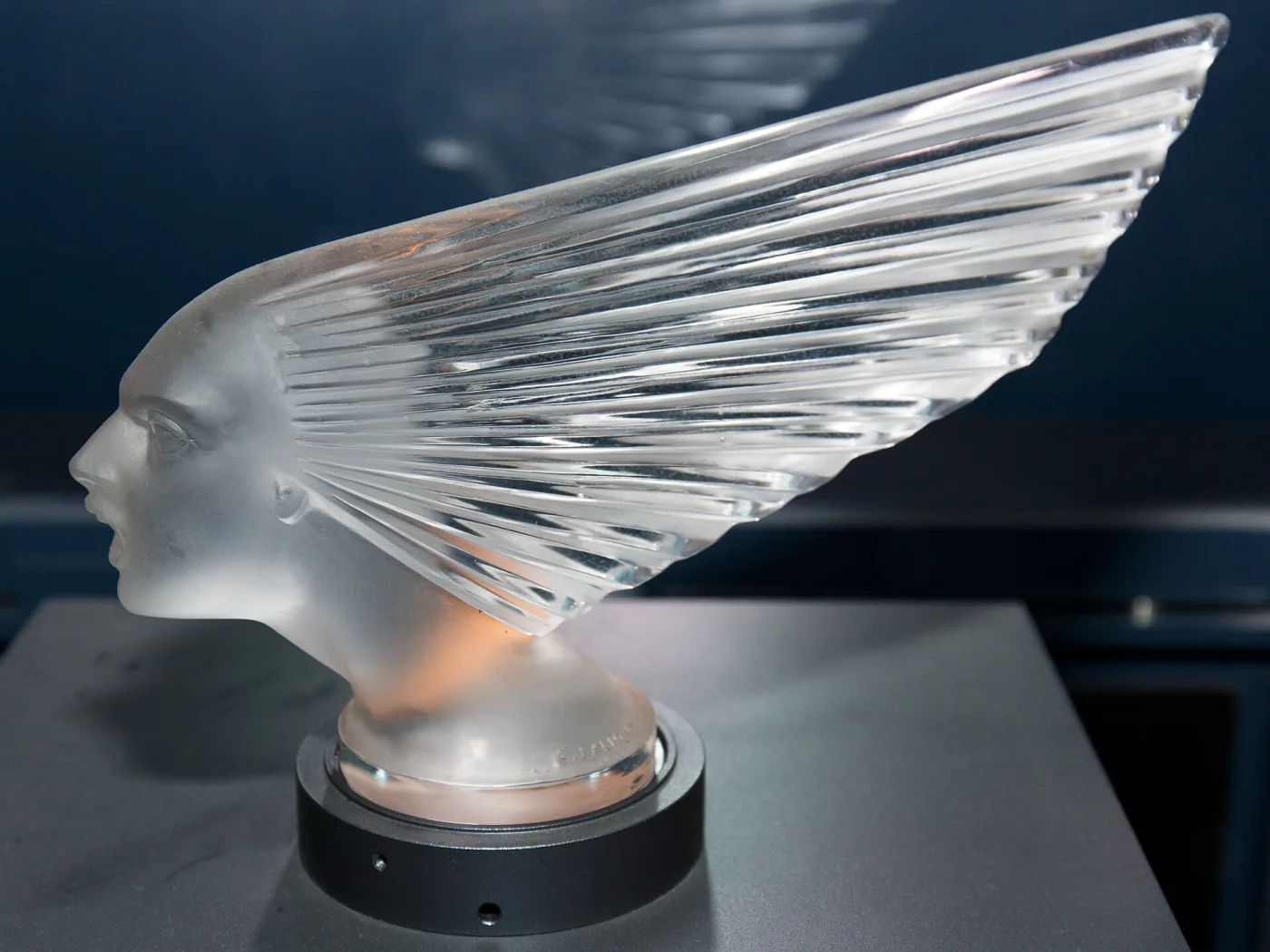 Frosted glass head of a woman with her hair streaming back in long sculpted flutes, mounted on a small base
