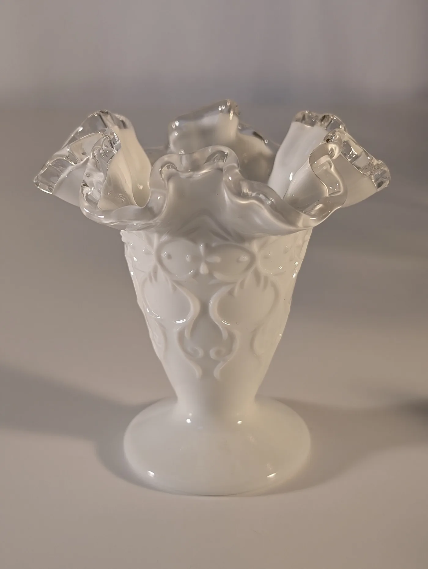 White milk glass vase with an embossed lace pattern and a colourless crimped glass edge