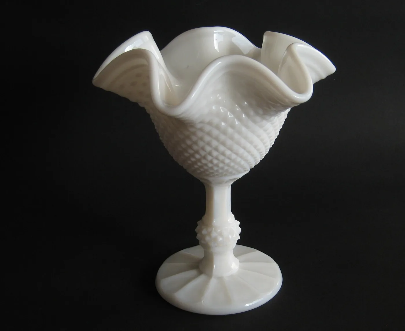 White milk glass pedestal bowl with a ruffled rim and a body covered in pointed diamond-shaped bumps