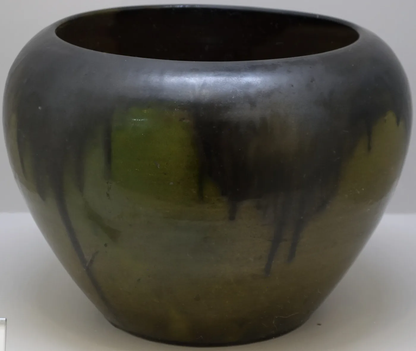 Wide low bowl in dark glossy glaze running from near-black at the rim to olive green and brown down the sides, with no carved or painted decoration