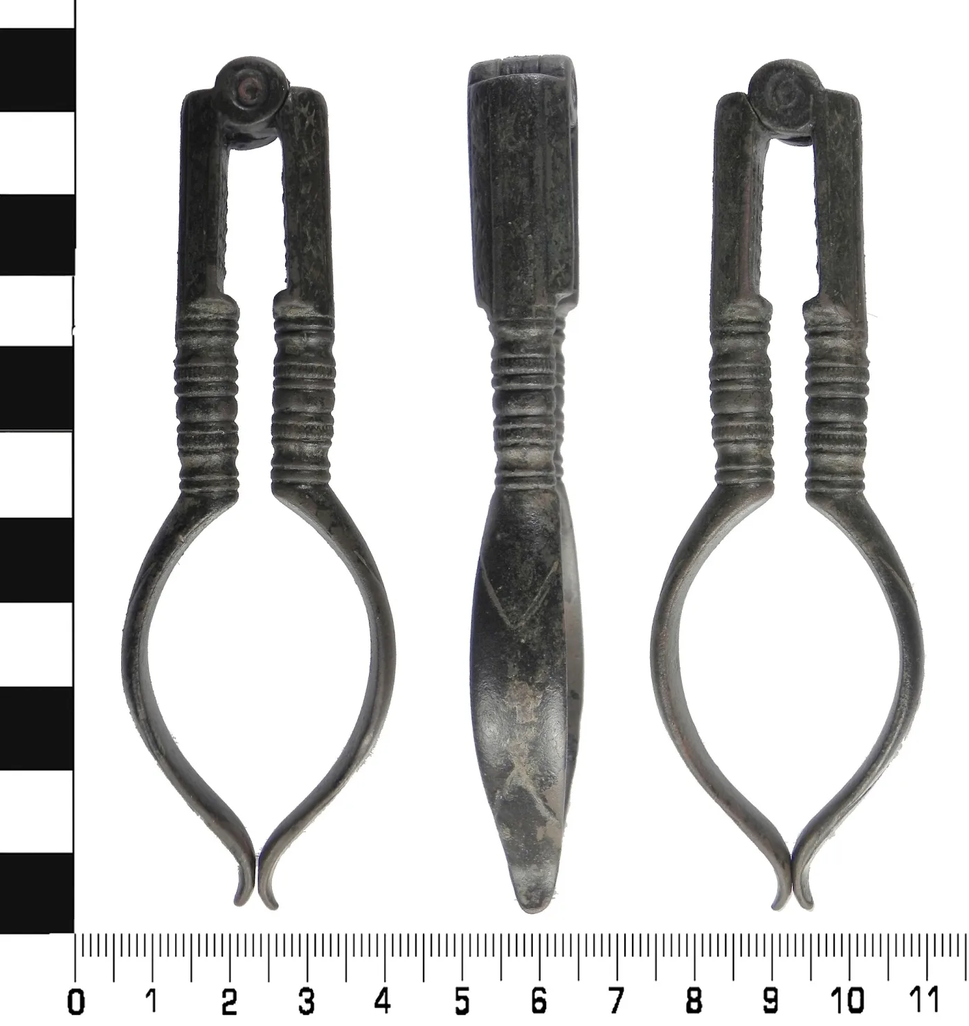 Three views of a complete pair of cast copper-alloy nutcrackers against a centimetre scale: the hinged front, a side profile, and the back