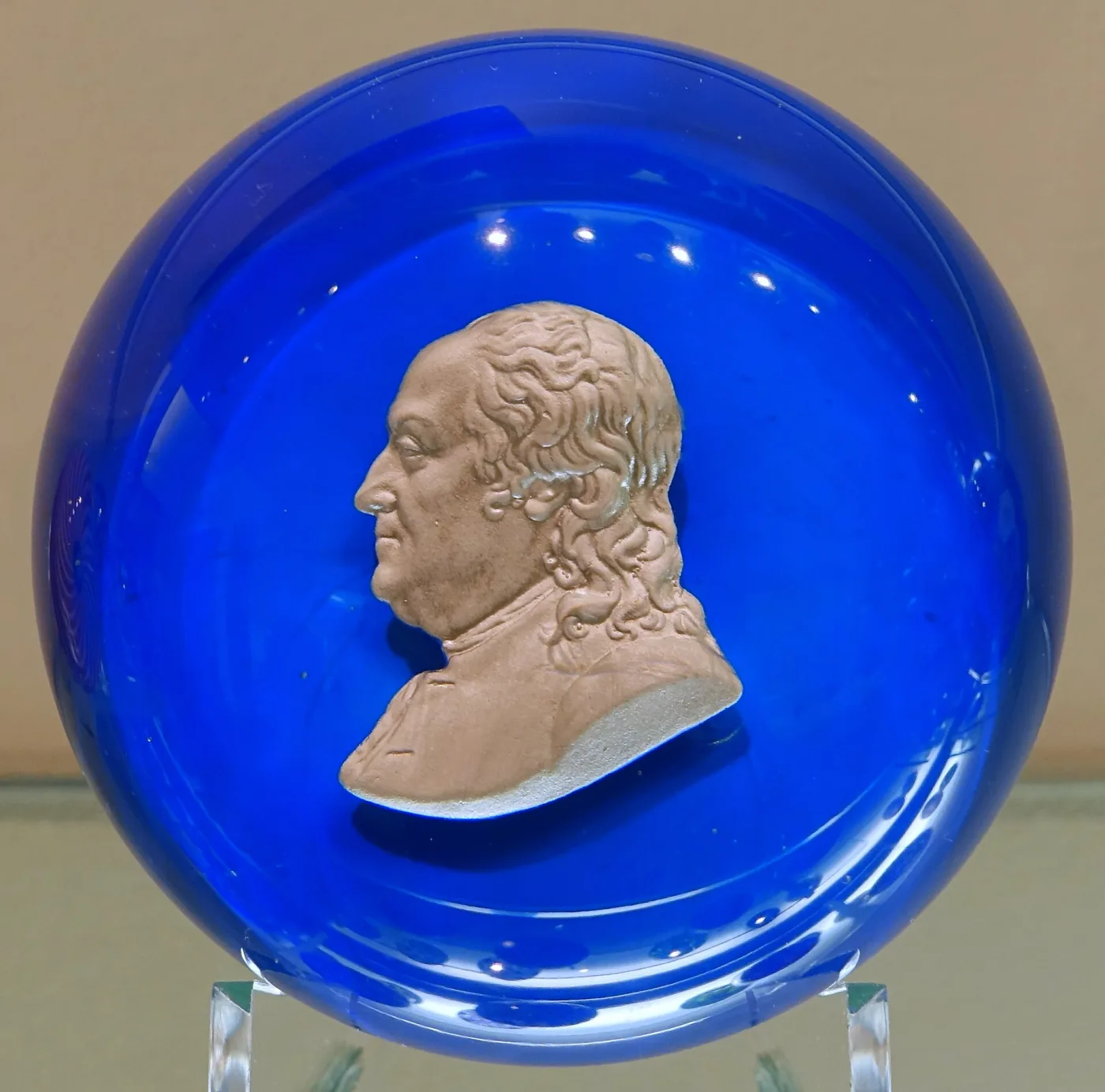 Paperweight with a deep blue opaque ground enclosing a white cameo-like profile bust of a bearded man in relief