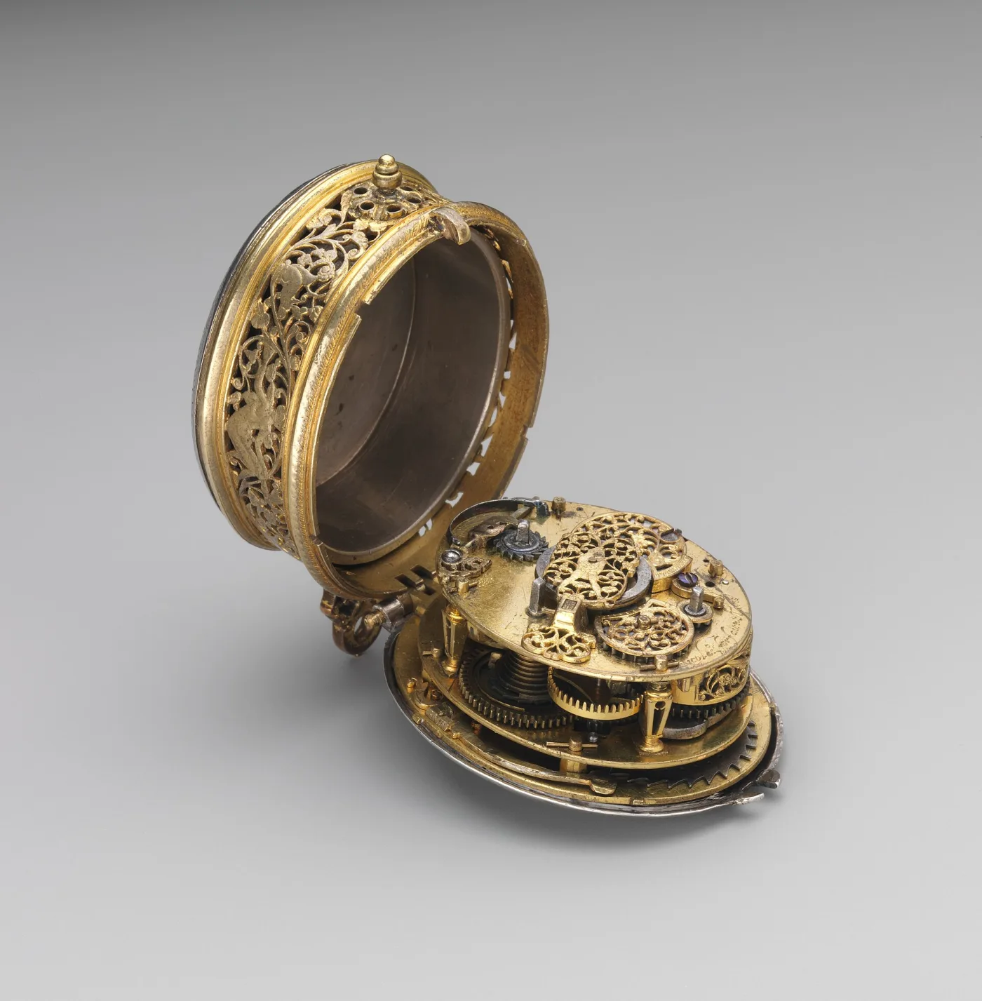 Small oval gilt watch case hinged open, the pierced and engraved case band on the left and the gilt movement with a tapering grooved fusee on the right