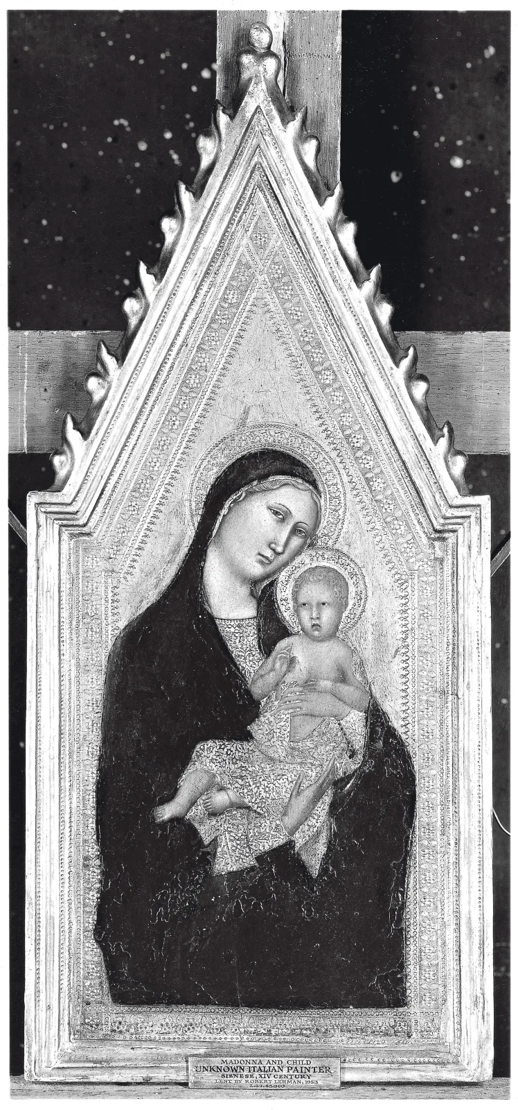 Fourteenth-century gabled tabernacle frame photographed in black and white, still integral with its painted Madonna and Child panel, the moulding rising to a pointed gable with pinnacles