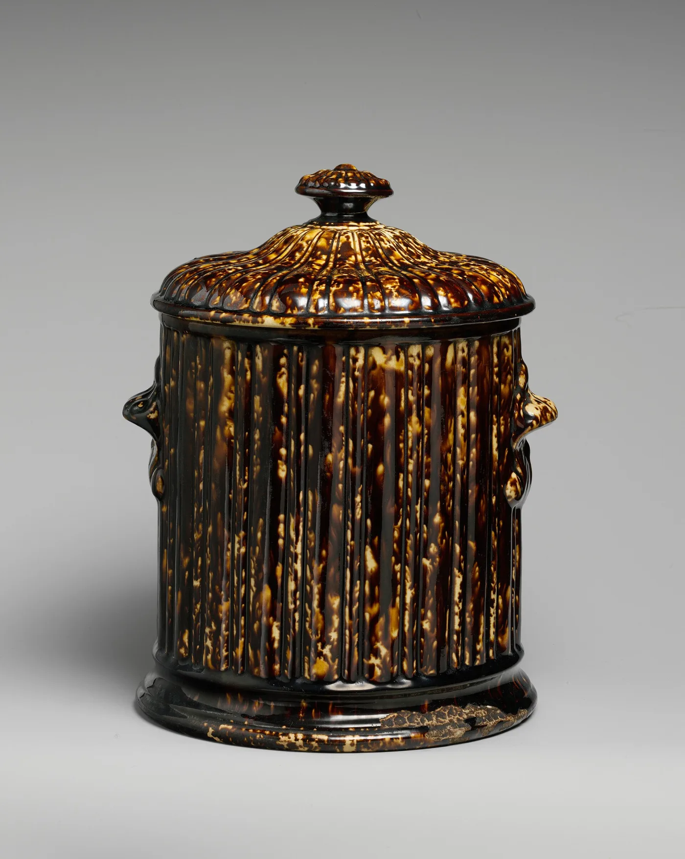 Cylindrical ribbed ceramic tobacco jar with a domed lid, glazed in streaked brown, ochre and cream