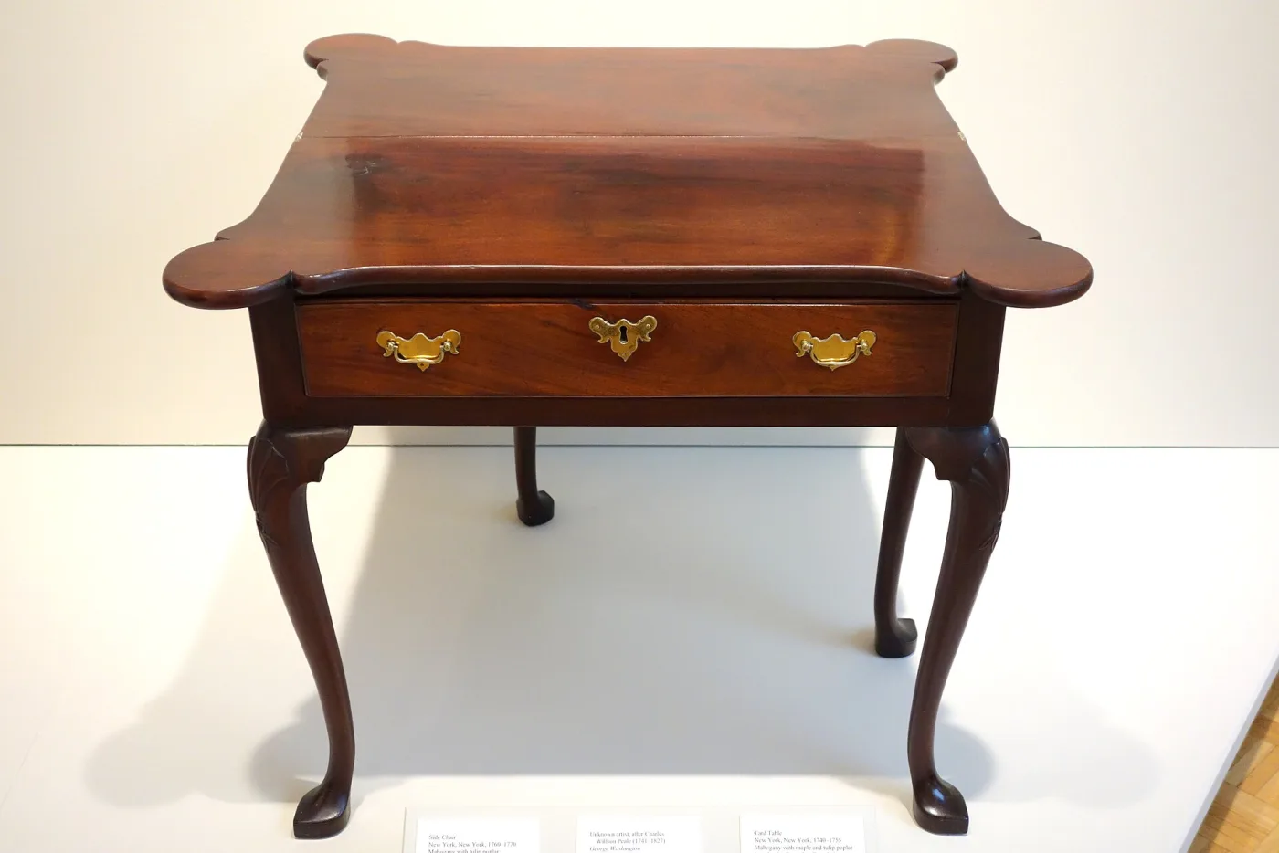 Mahogany card table with a shaped top, brass drawer handles and cabriole legs with lightly carved knees ending in pad feet