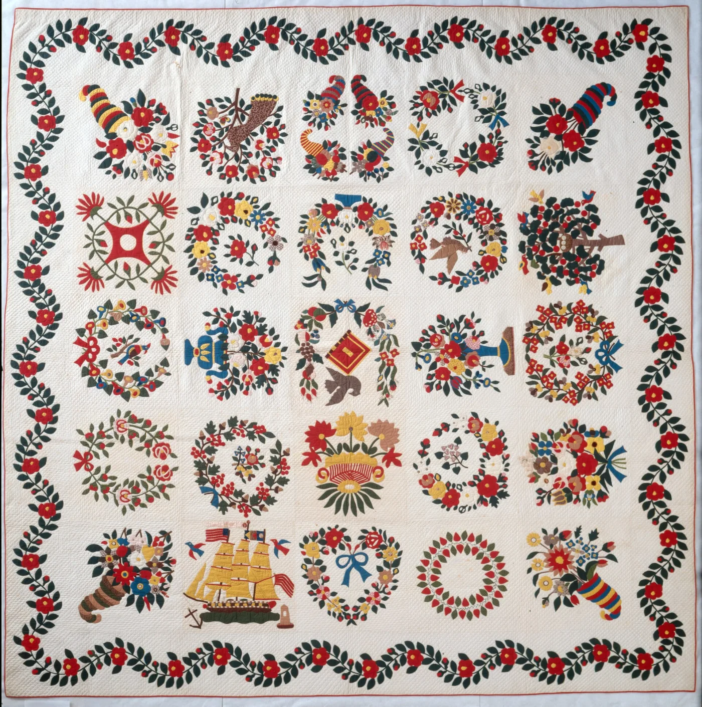Album quilt of twenty-five appliqu&eacute;d blocks in red, green and yellow on white, each a wreath, basket or cornucopia, framed by a red-and-green floral swag border