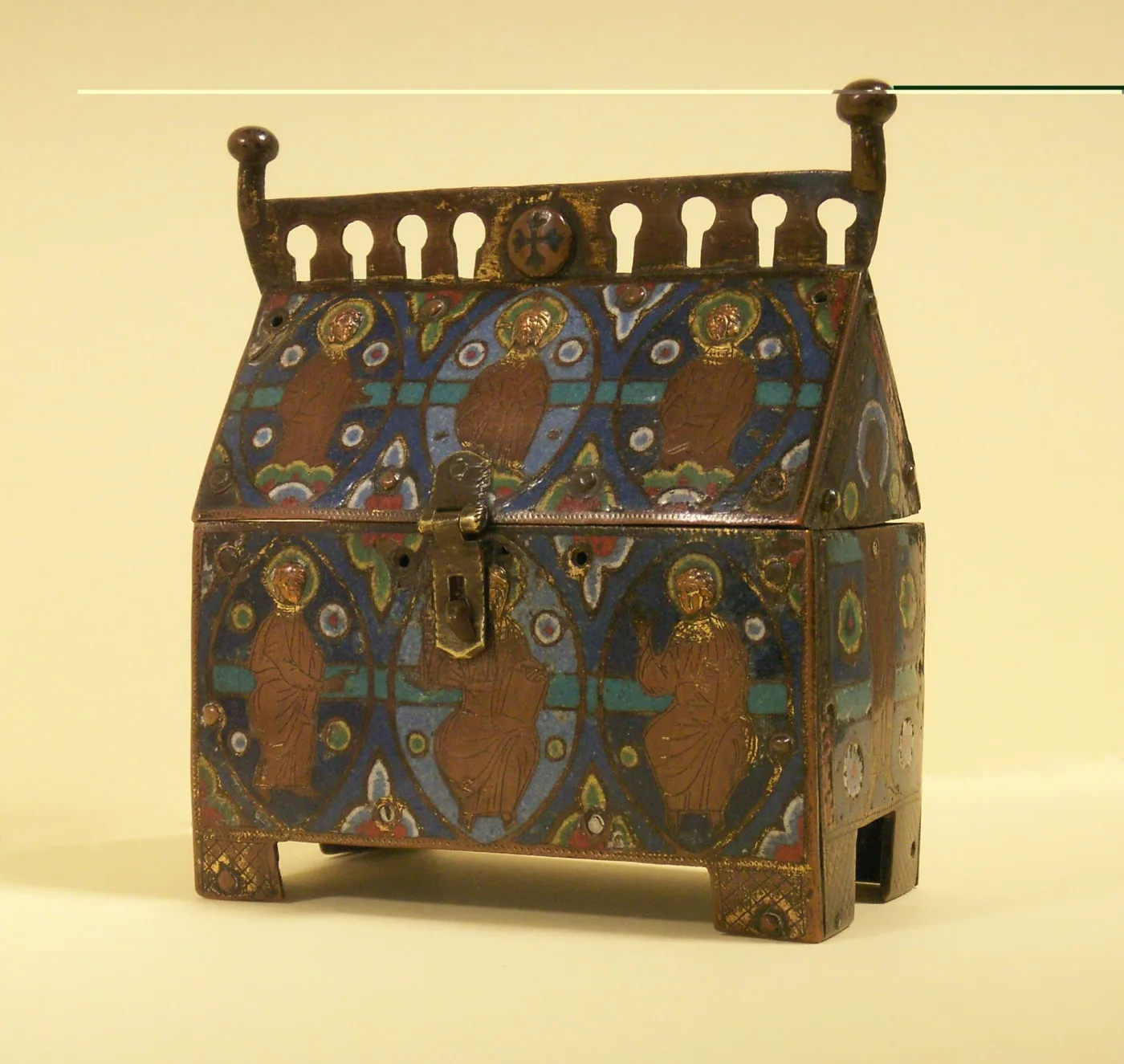 House-shaped reliquary casket with a pitched roof and gabled ends, its copper surface enamelled in deep blue with gilded figures of saints in roundels and a hinged clasp at the front