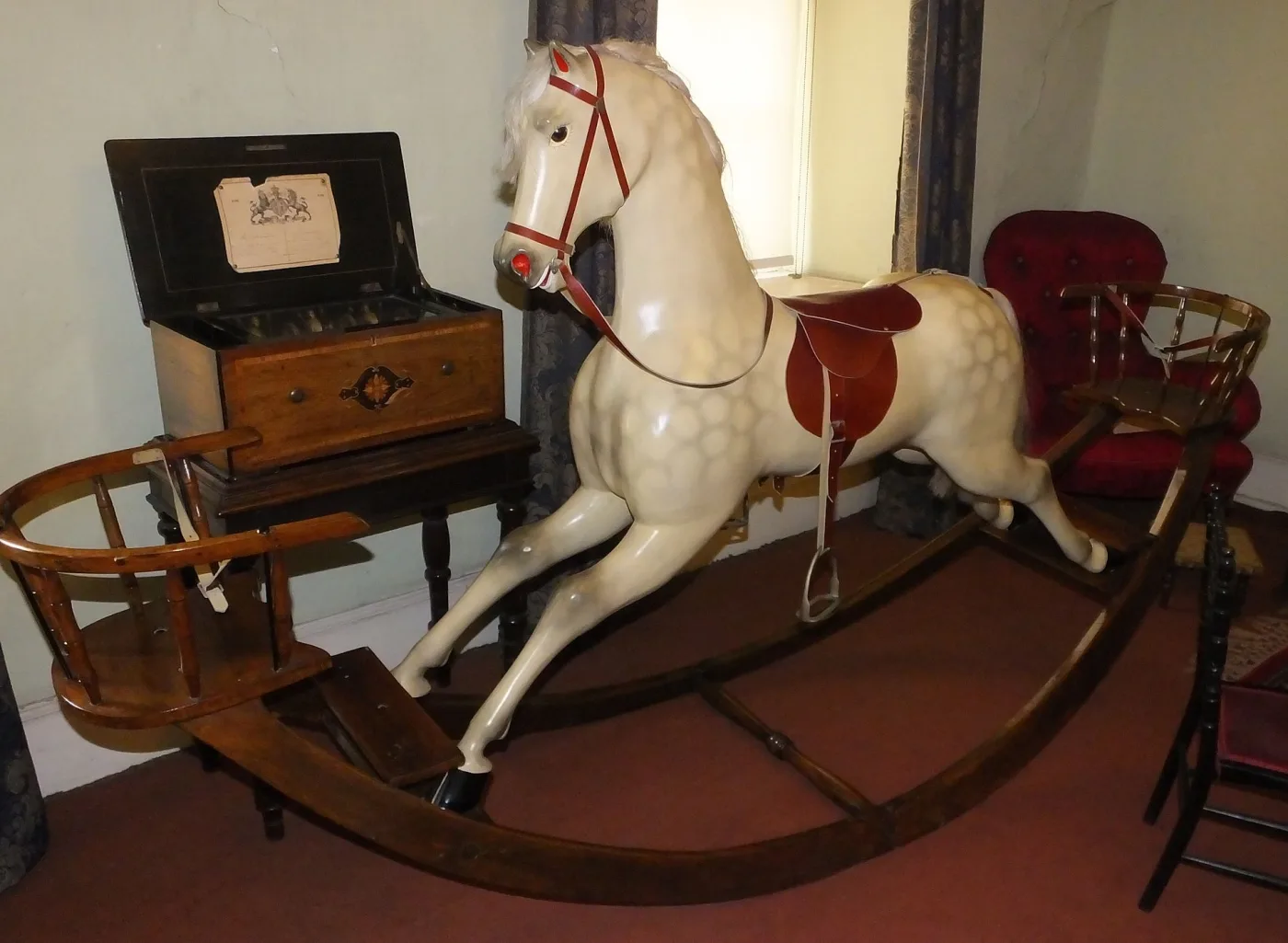 Large dapple grey rocking horse with soft grey dapples and a red leather saddle, mounted on a long bow rocker with a bentwood child seat at each end