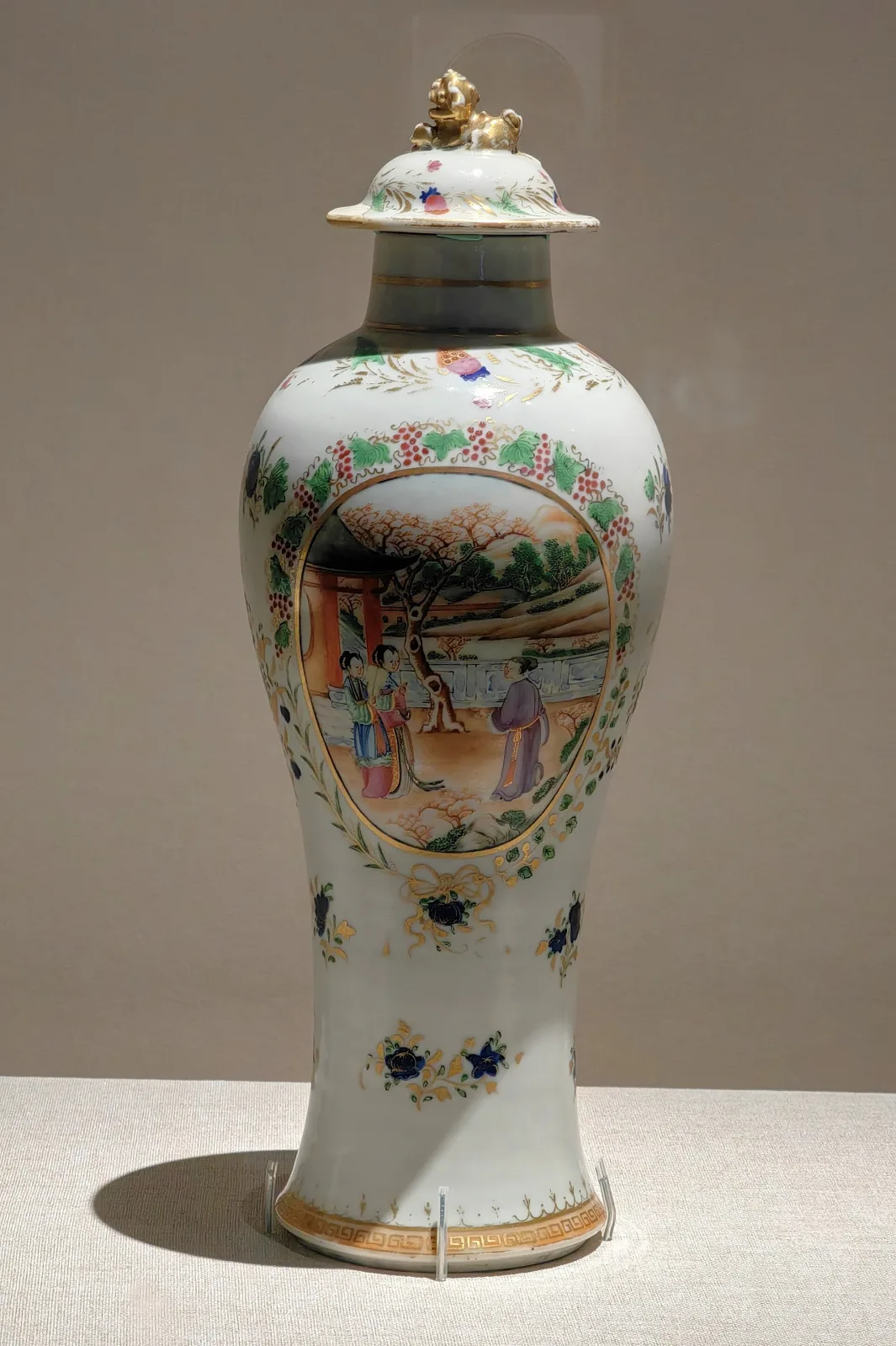 Qing dynasty Cantonese enamelled meiping vase with cover and a gilt lion finial, decorated with one large figure panel in a gilt and floral frame on an otherwise plain white ground scattered with small flower sprays