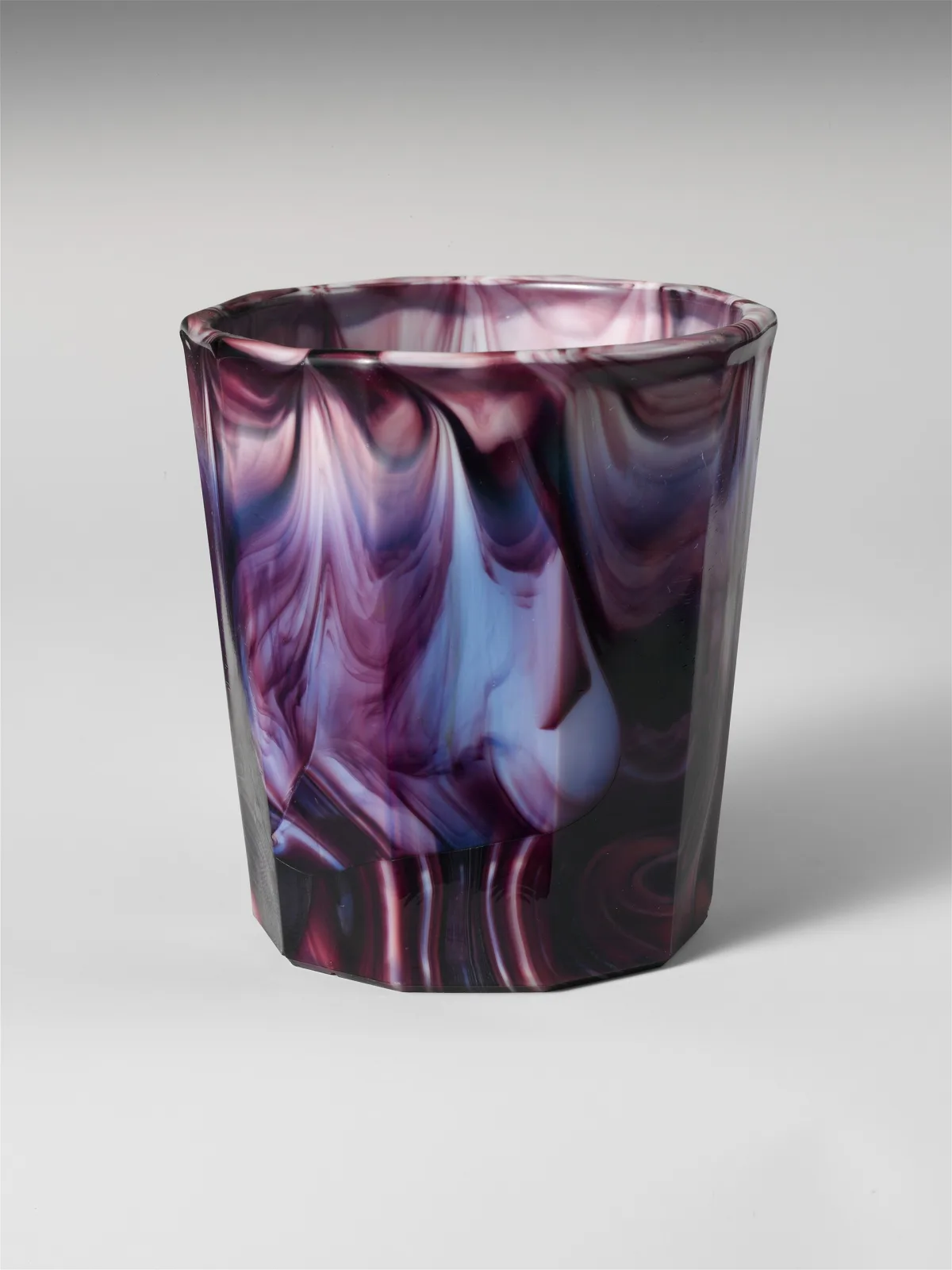 Ten-sided purple and white marbled glass tumbler, plain-walled, the marbling running vertically through the glass with faint vertical seams at the panel joins