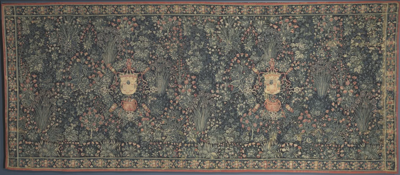 Wide millefleurs tapestry of the early sixteenth century, its whole ground covered in small flowering plants on a dark field, with the Medici coat of arms in a wreath at the centre
