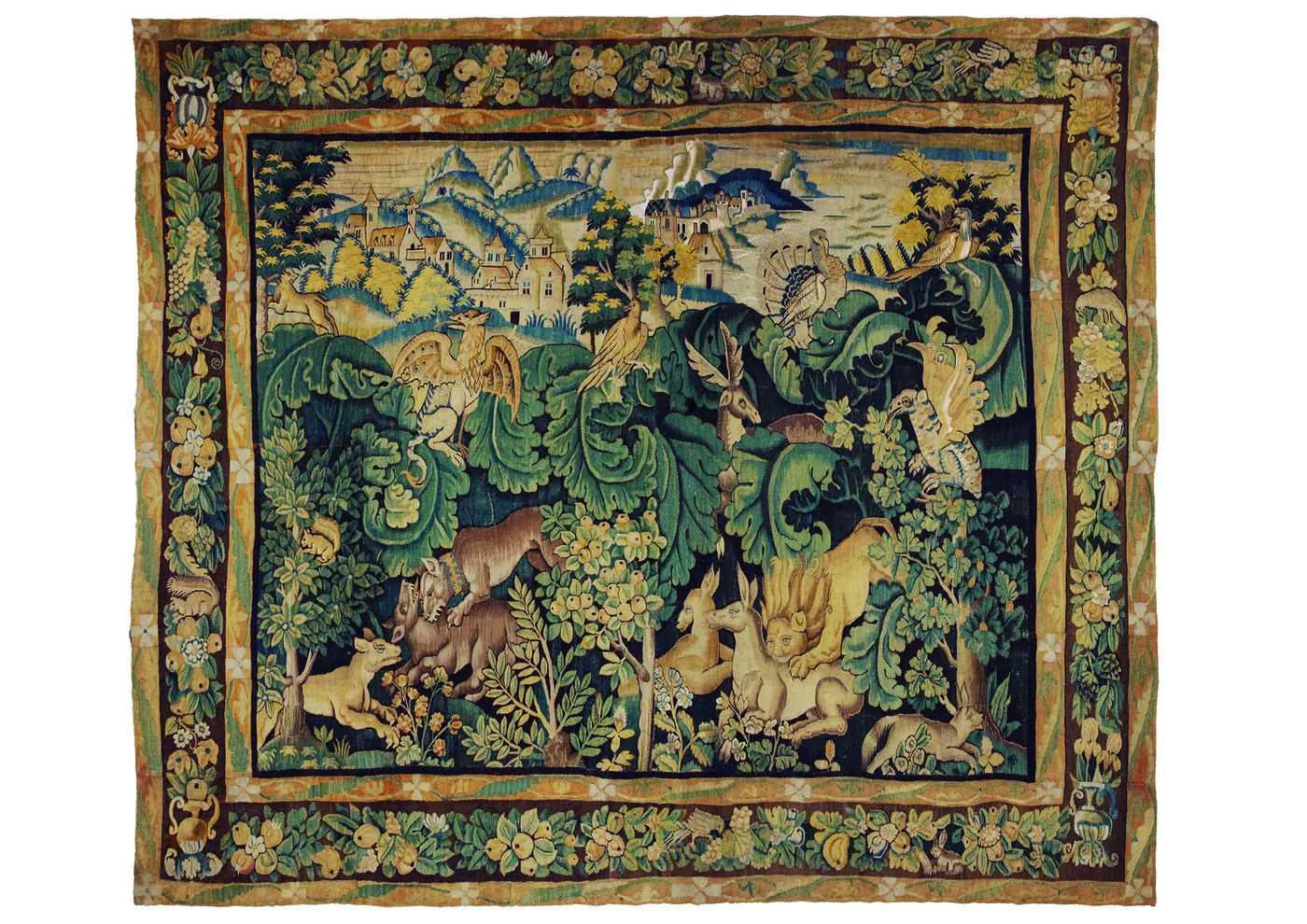 Sixteenth-century verdure tapestry filled with large fleshy cabbage-like leaves in green and yellow, with does, a lion and birds among them, a walled town in the distance, and a wide flowered border