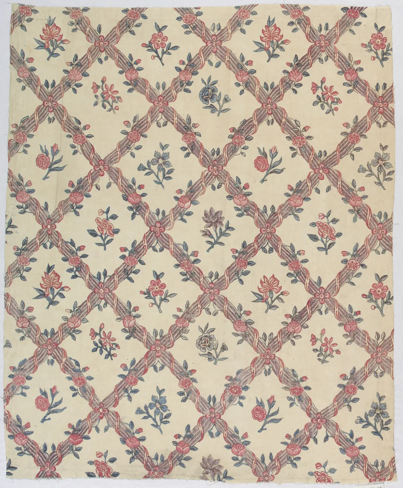 Eighteenth-century Indian chintz printed with a diamond lattice of columns and curving ribbons enclosing floral sprays, in soft reds, browns and blue-greens on a cream cotton ground