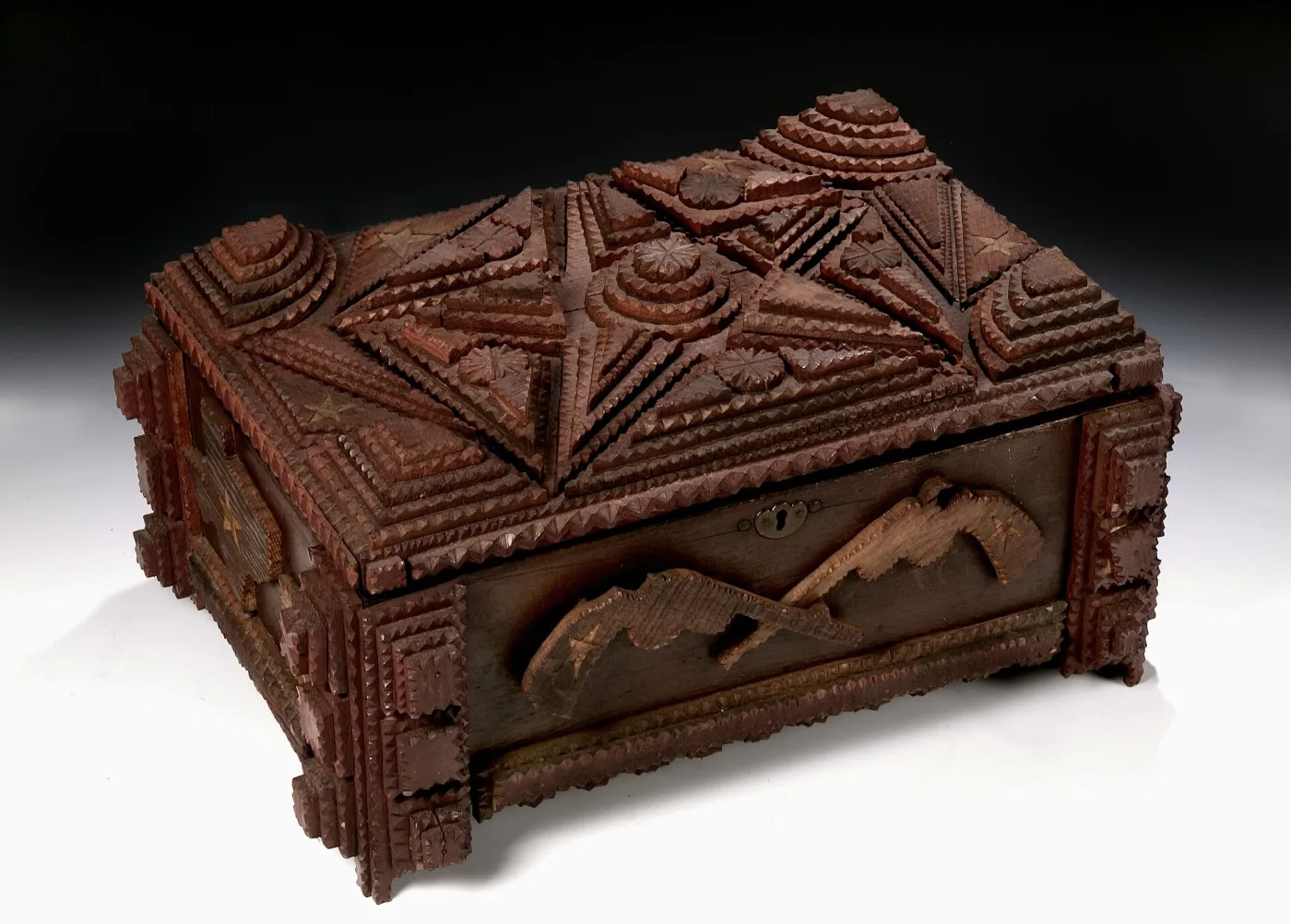 Dark red-brown wooden casket with a lid built from stacked diamond and stepped-pyramid panels, every edge cut into fine sawtooth notches, with inlaid light-wood stars