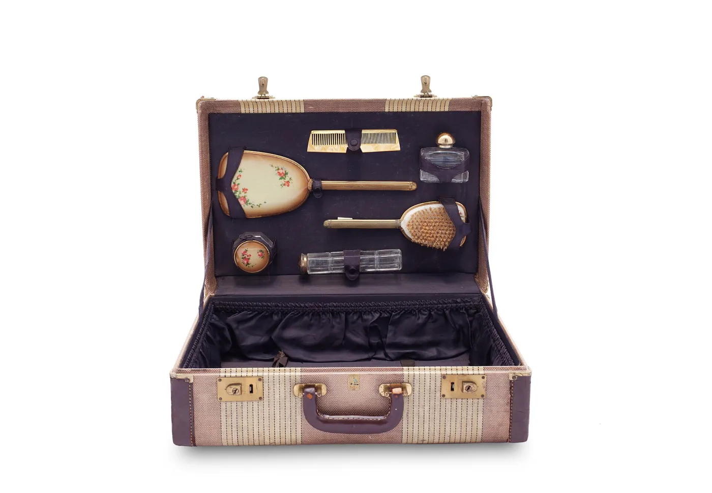 Open fitted vanity case lined in mauve, its lid holding a mirror and its tray fitted with silver-backed brushes, a hand mirror, jars and small tools each in a shaped recess
