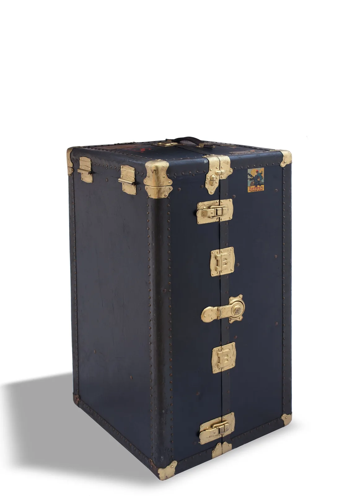 Tall wardrobe trunk standing on end, bound in dark material with leather corner caps and edge binding, and fitted with two large brass locks and several catches down the front
