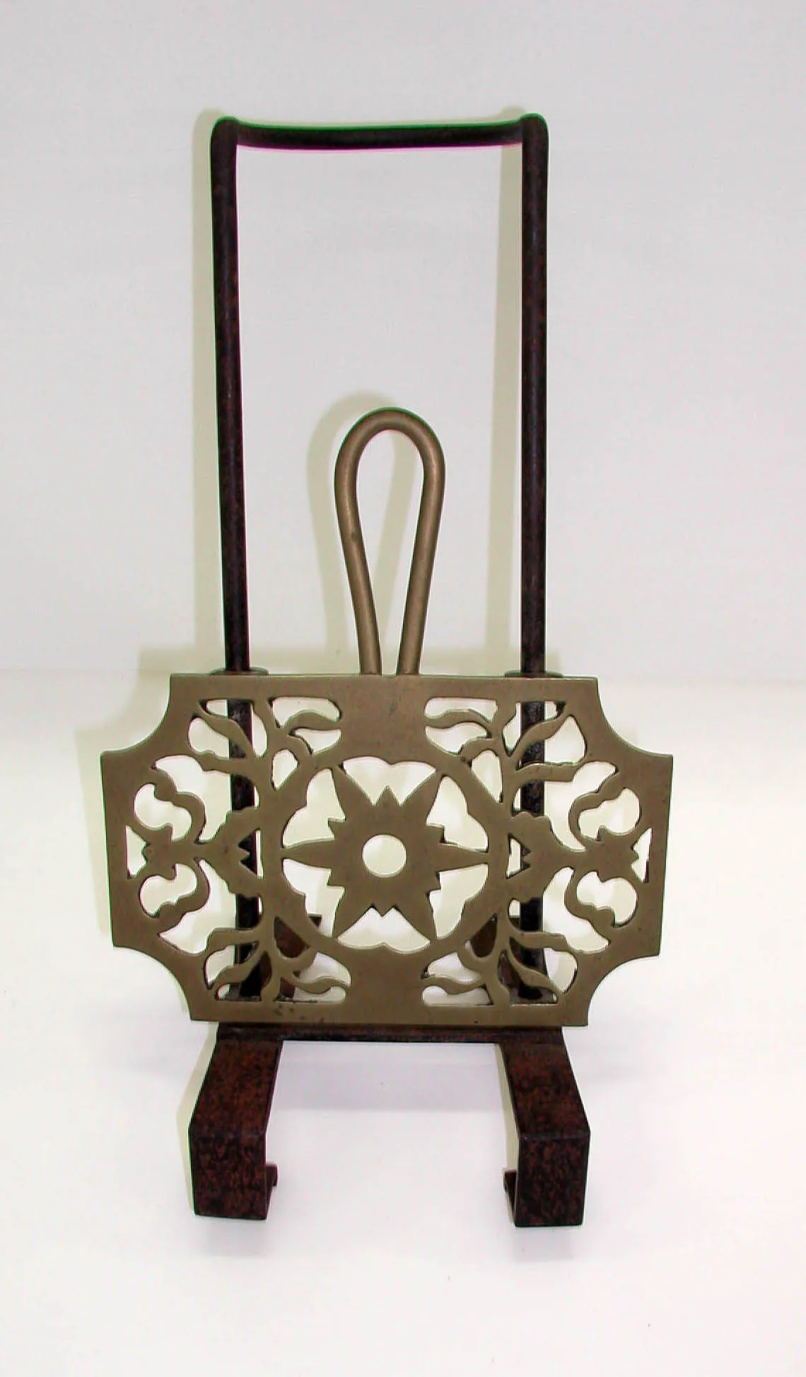 Iron fire-bar trivet with two long hooked arms behind and a pierced brass top plate cast with a star and scrolling foliage