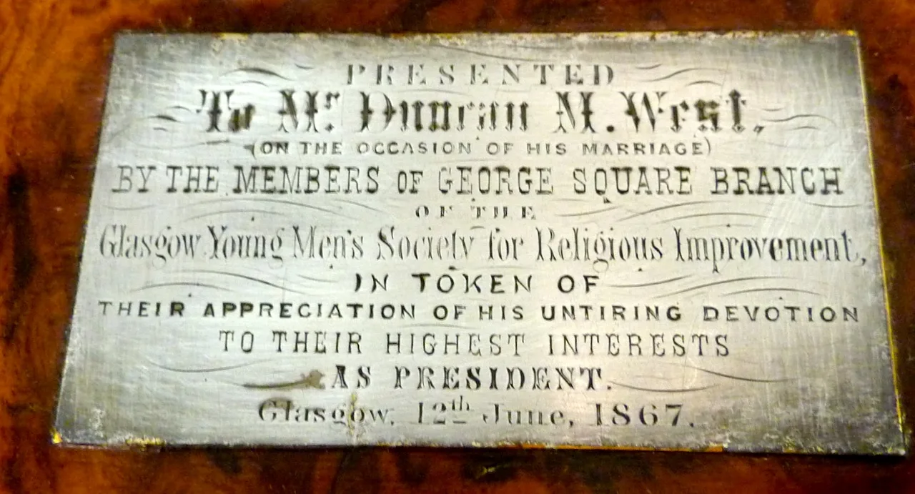 Engraved metal plaque let into a burr walnut surface, its inscription recording a presentation to a named man on his marriage, dated Glasgow 1867