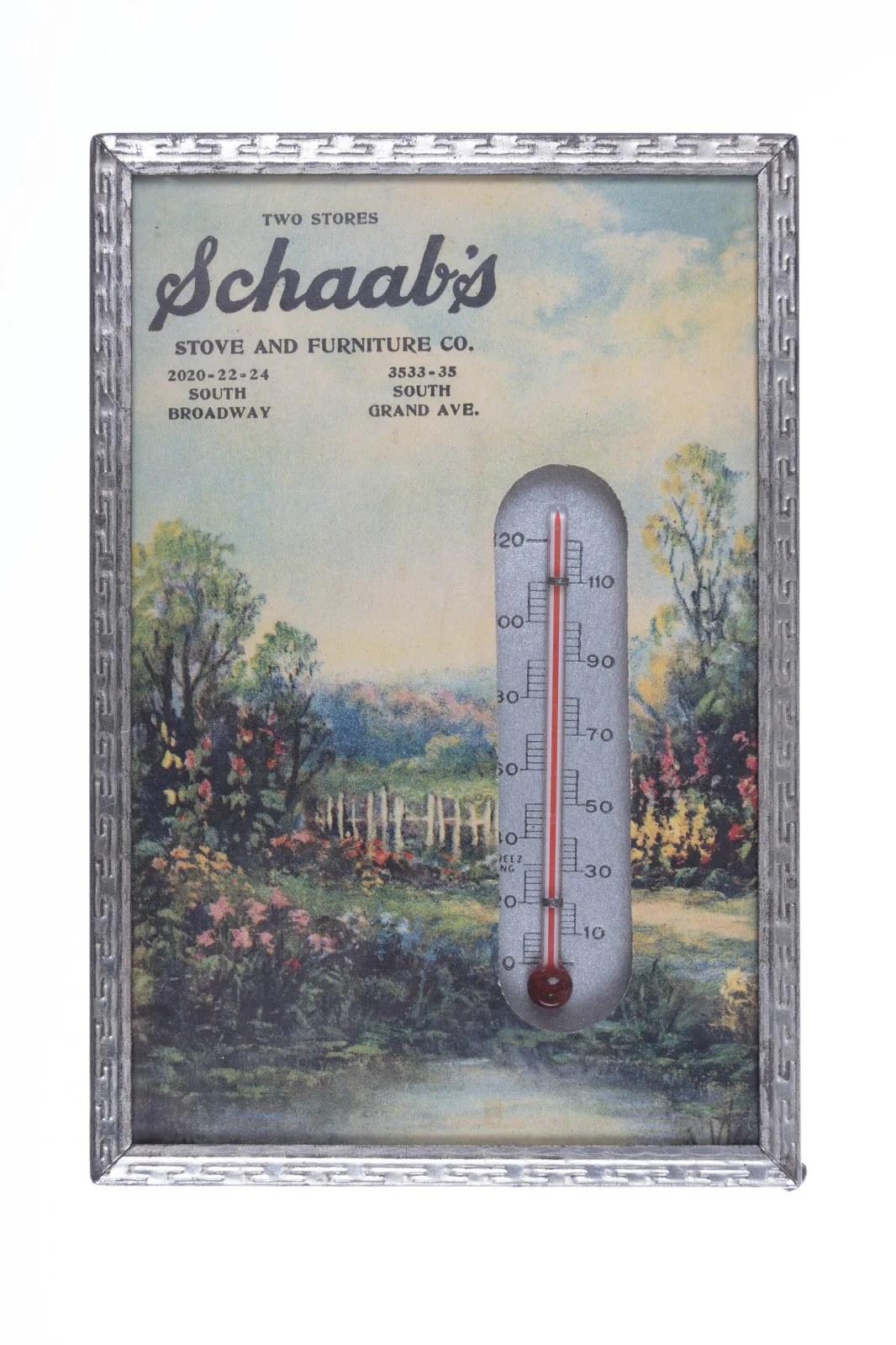 Rectangular advertising thermometer with a lithographed pastoral scene of a woman in a garden, an arched thermometer set into the centre and the retailer's name and address printed above