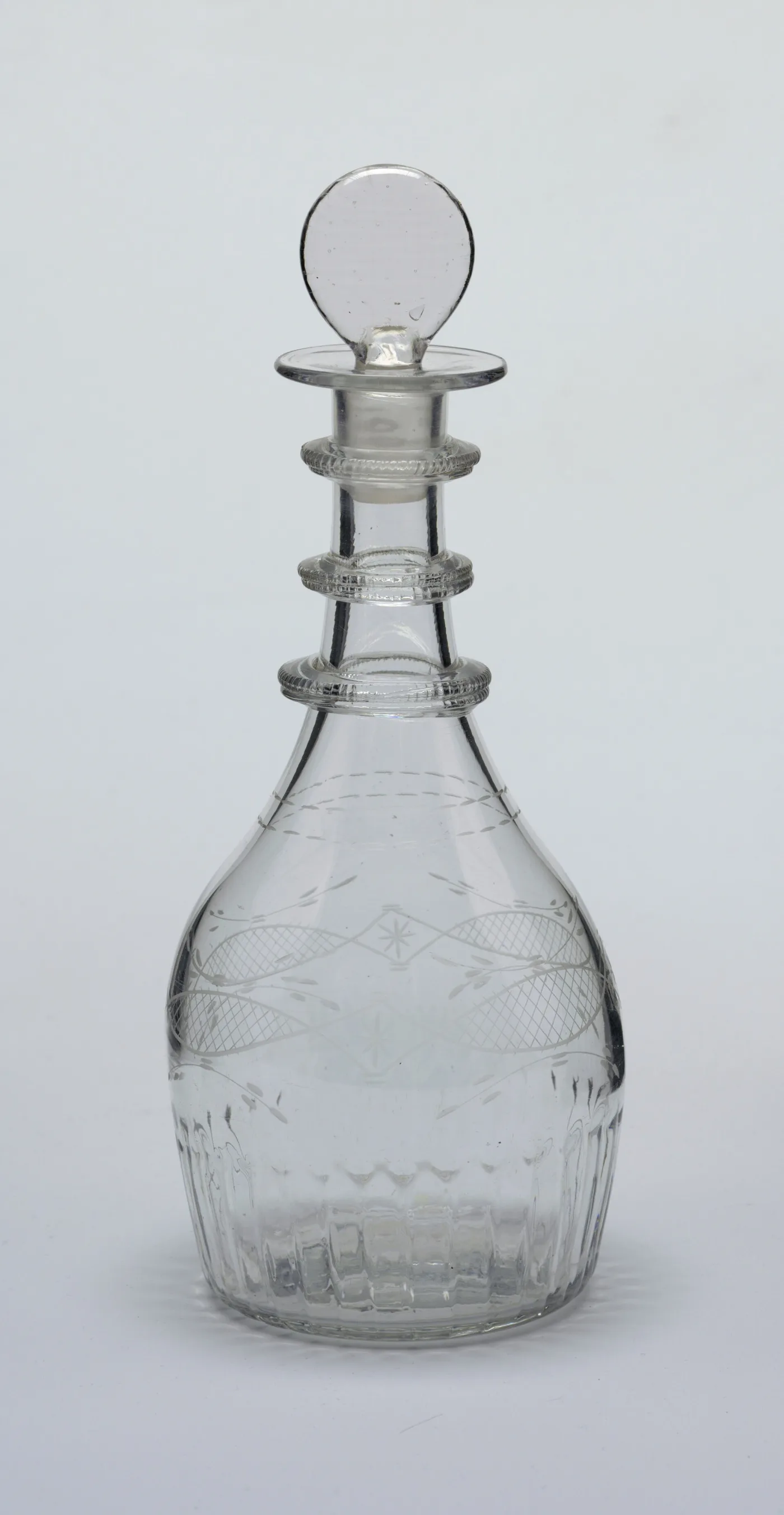 Tapered Irish decanter with three notched neck rings, an engraved band of crossed ovals and stars, and a moulded target stopper