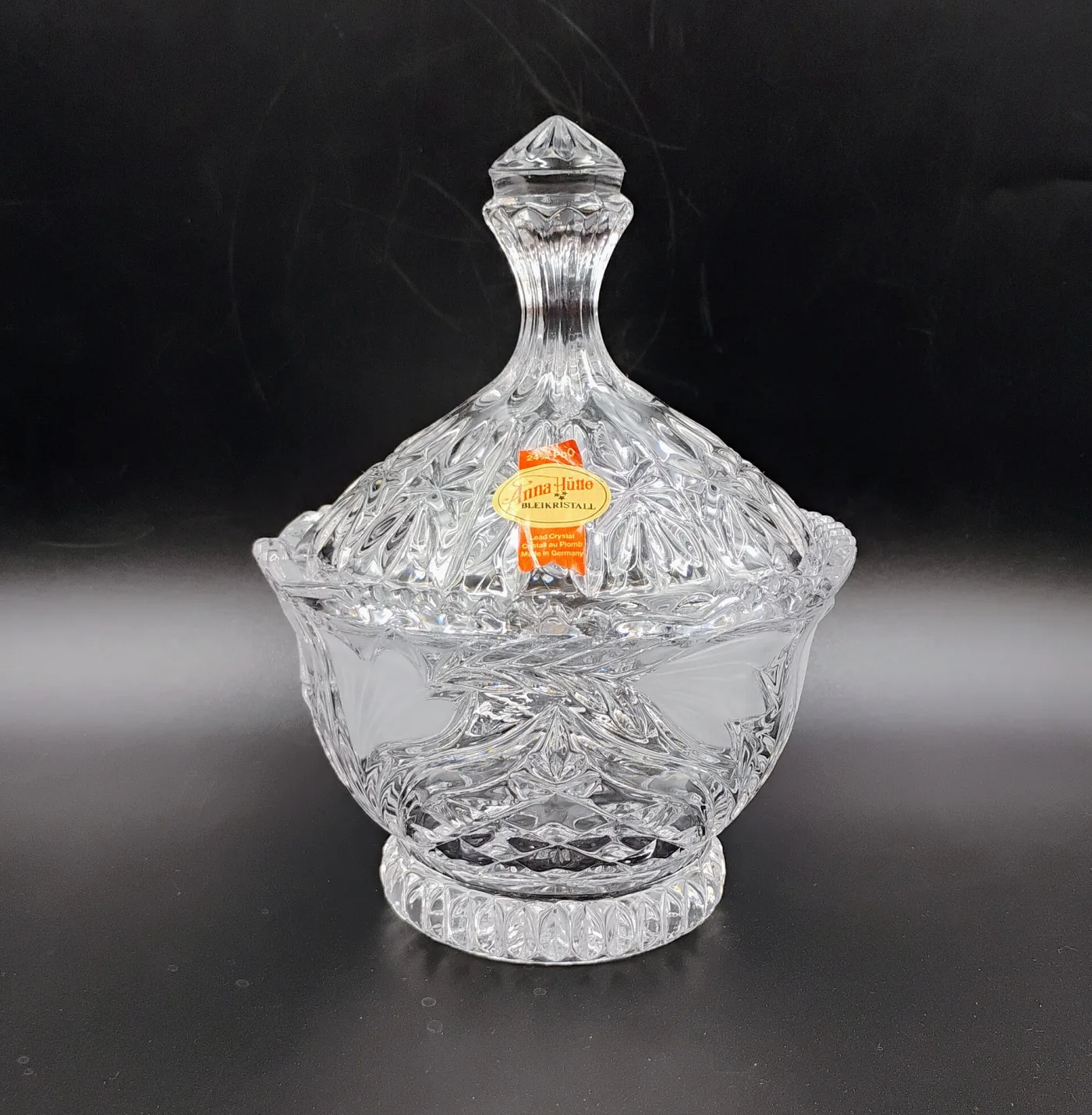 Covered crystal bonbon dish with moulded leaf and diamond ornament and frosted flowers, carrying an orange oval label reading Anna Hutte Bleikristall