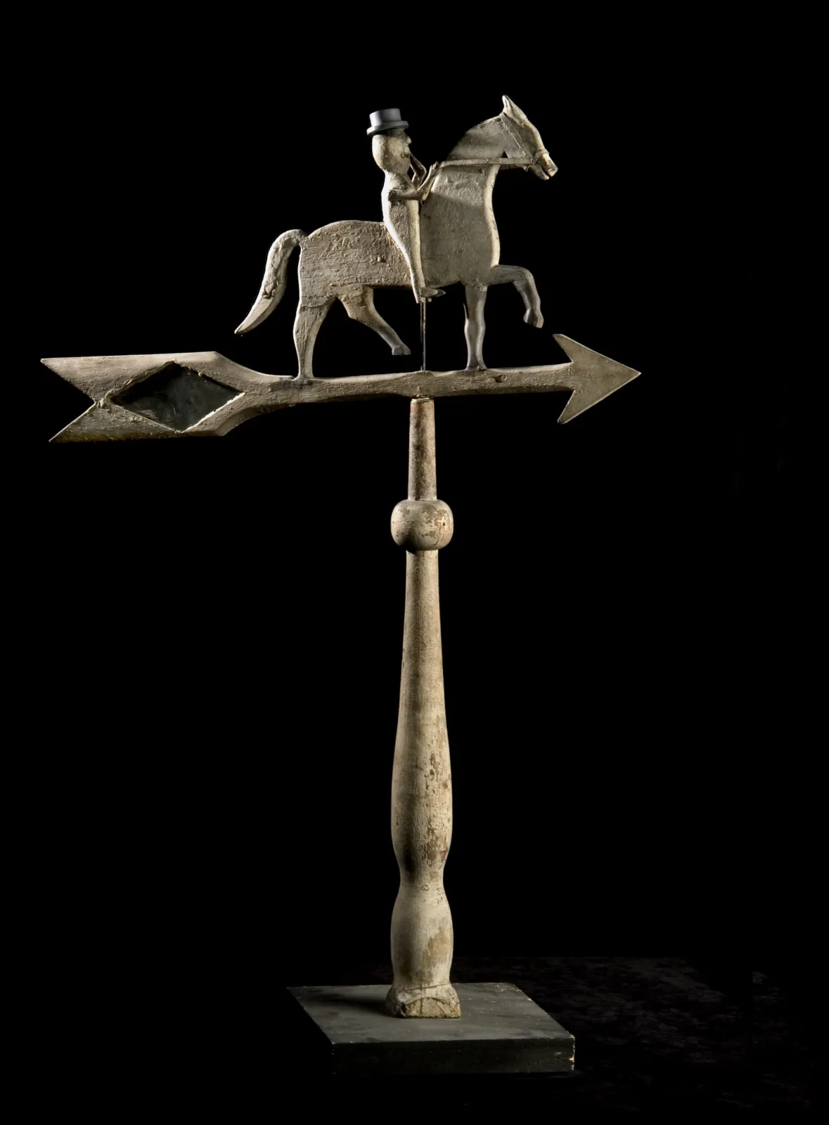 A carved and painted wooden weathervane of a rider on a prancing horse, the rider's eye made of inset glass