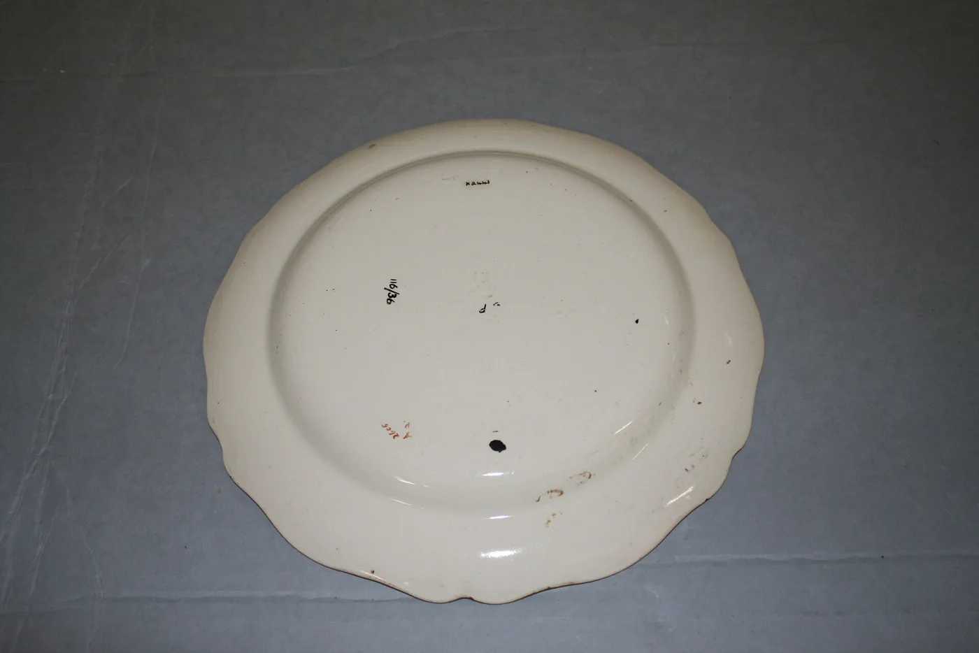 The same plate turned over, its plain cream underside showing the footrim and a small mark near the centre